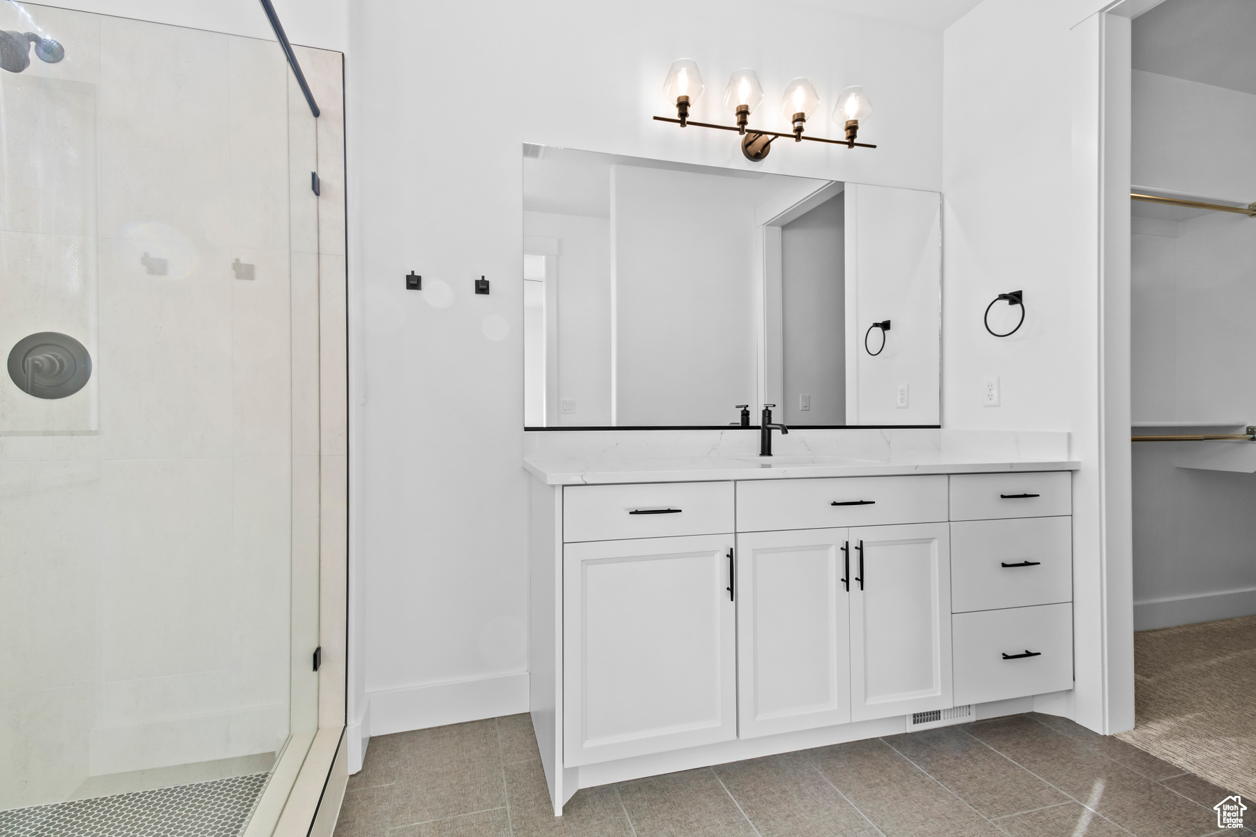 Bathroom featuring tile flooring, vanity, and a shower with shower door
