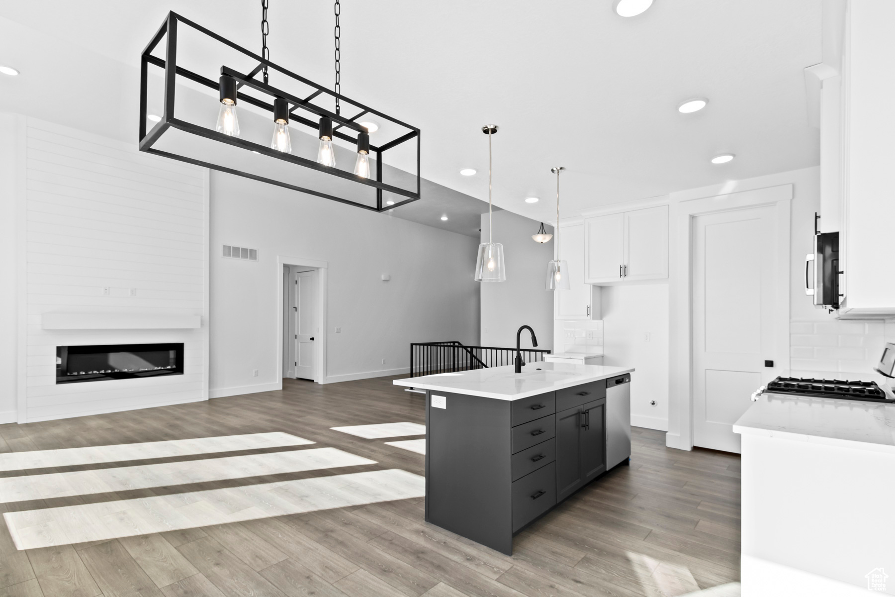 Kitchen with wood-type flooring, hanging light fixtures, gray cabinetry, white cabinetry, and tasteful backsplash
