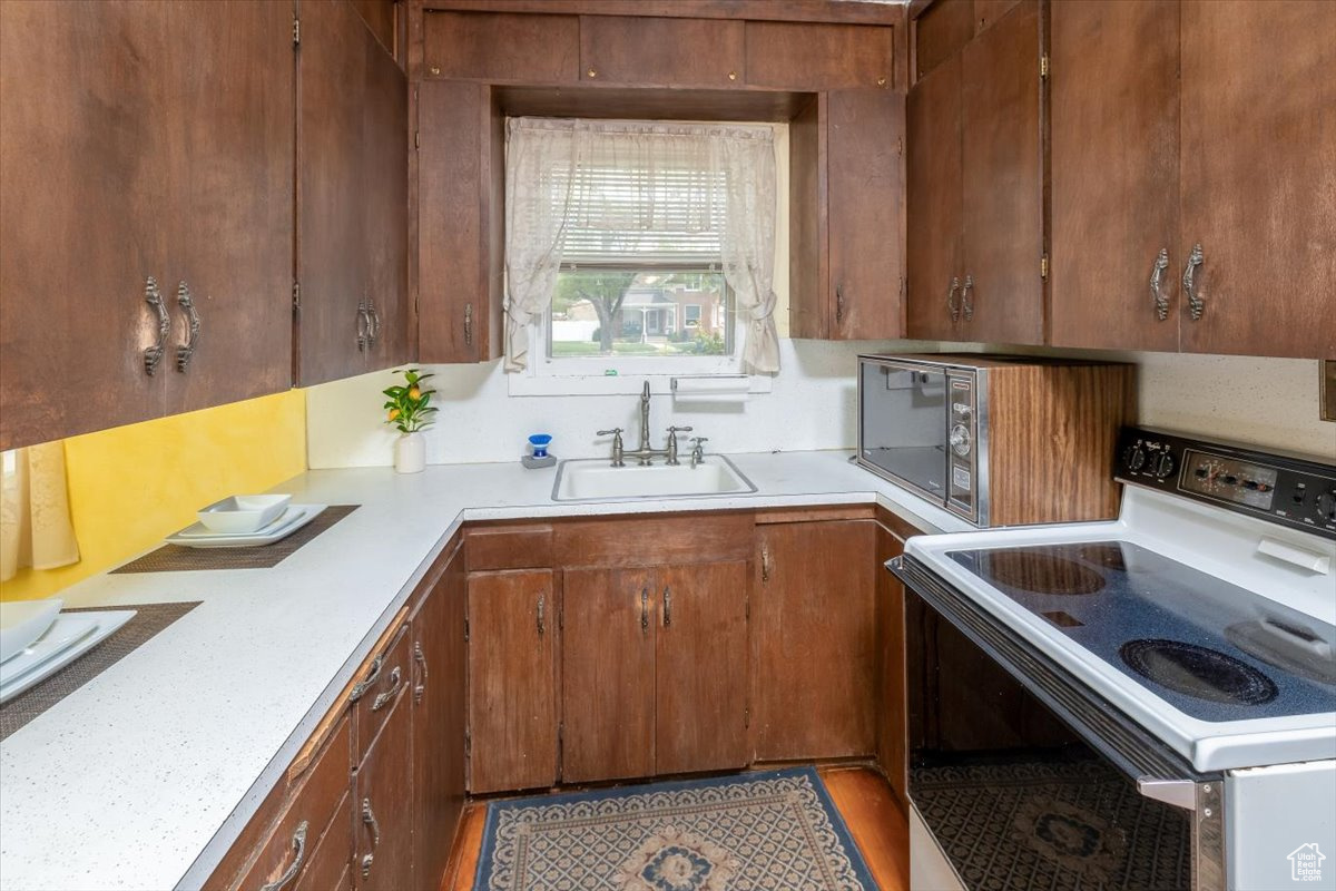 Kitchen with white range, microwave, sink, and hardwood / wood-style flooring