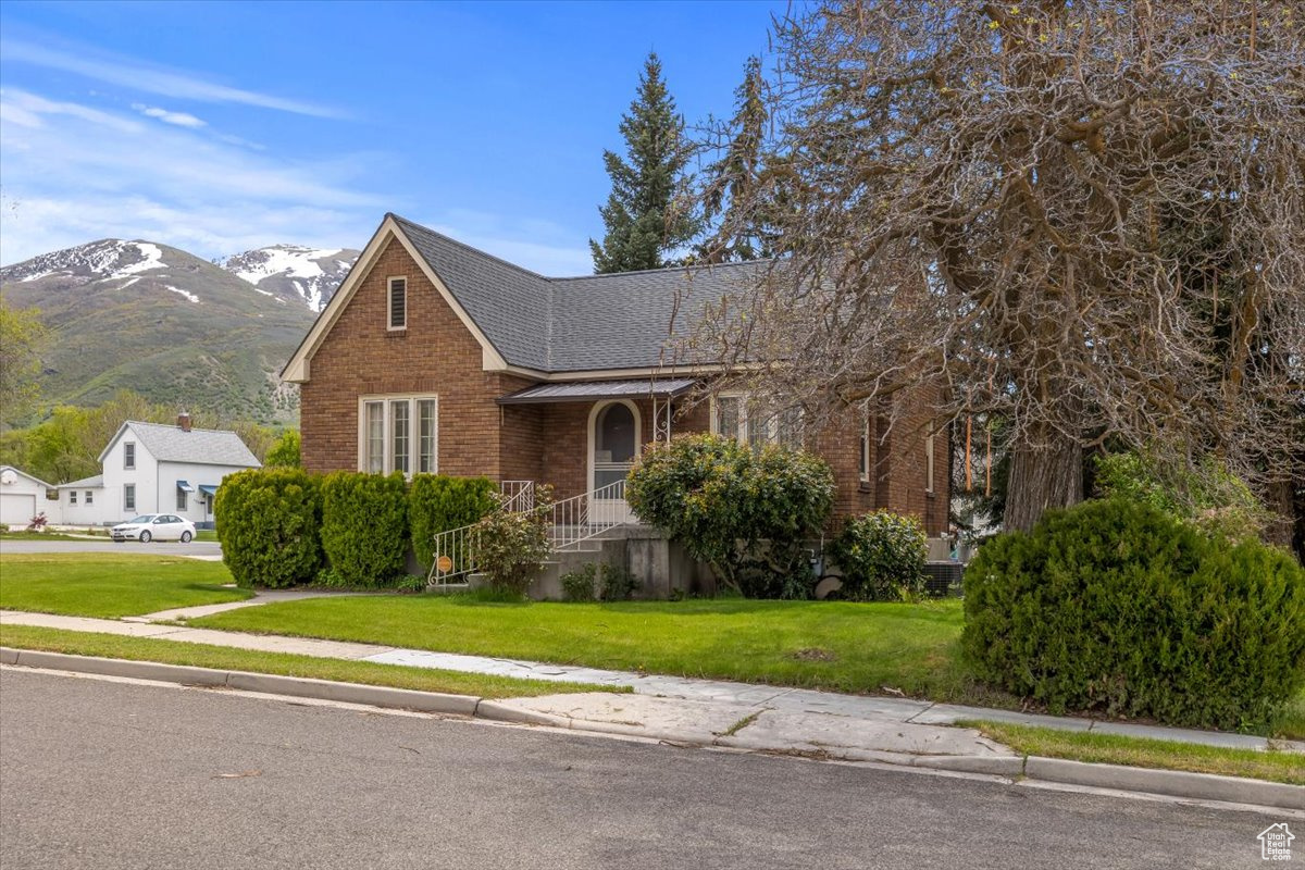 View of front of home with a front yard, a mountain view, and covered porch