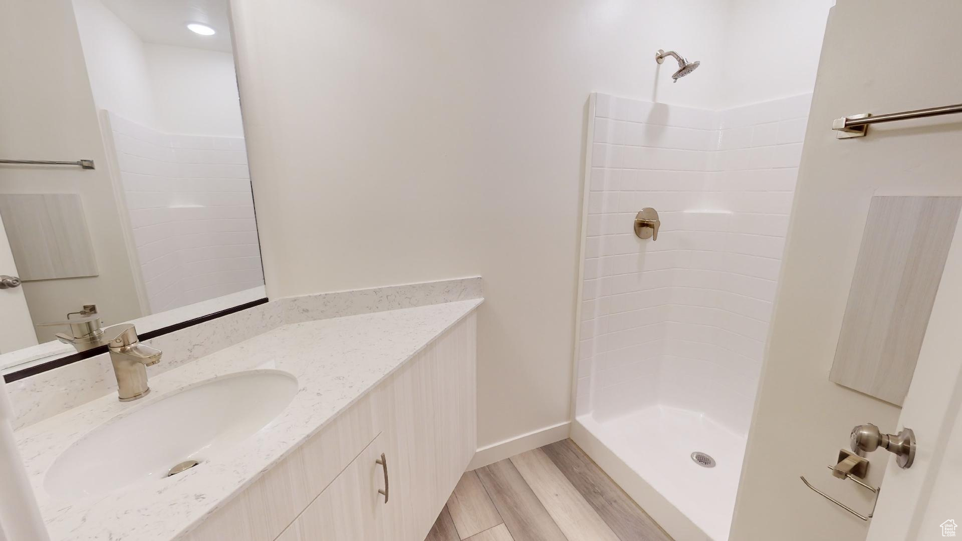 Bathroom with a shower, vanity, and hardwood / wood-style flooring
