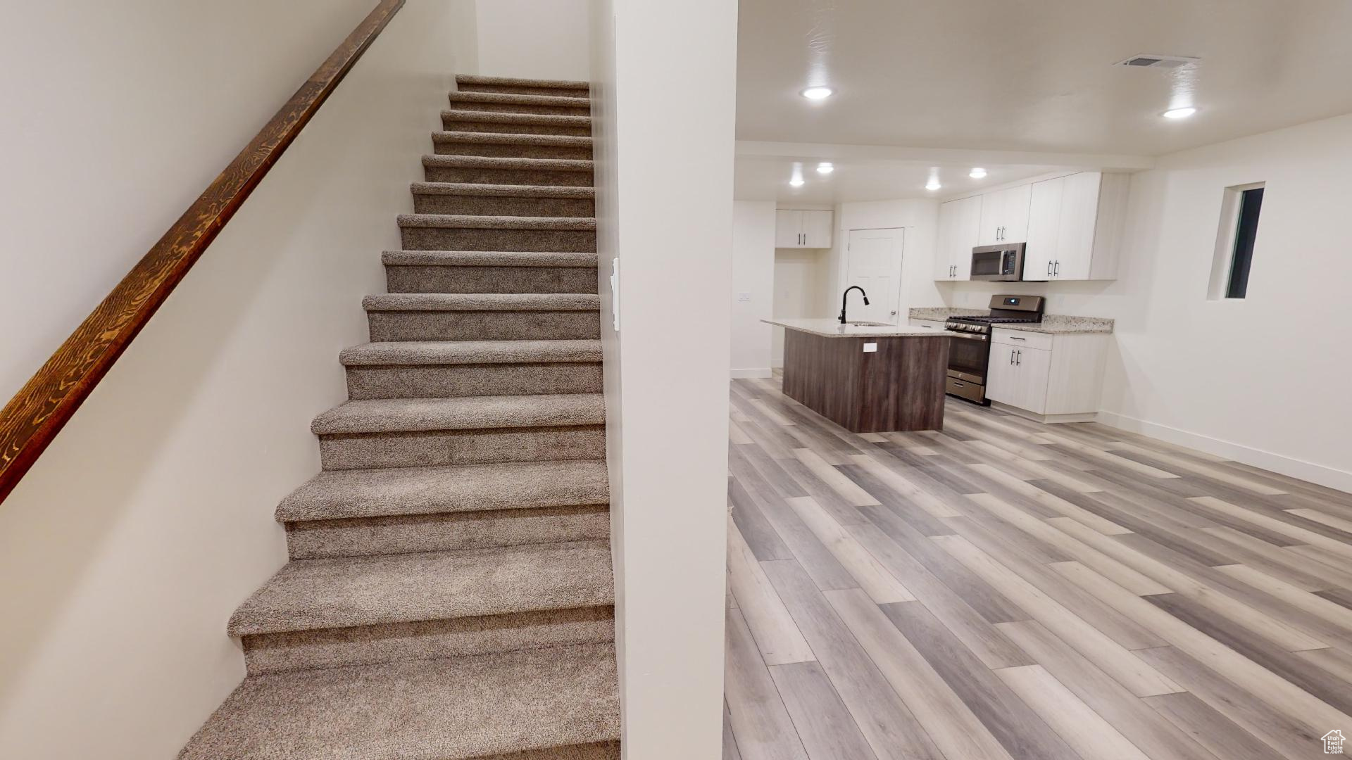 Staircase with light hardwood / wood-style floors and sink