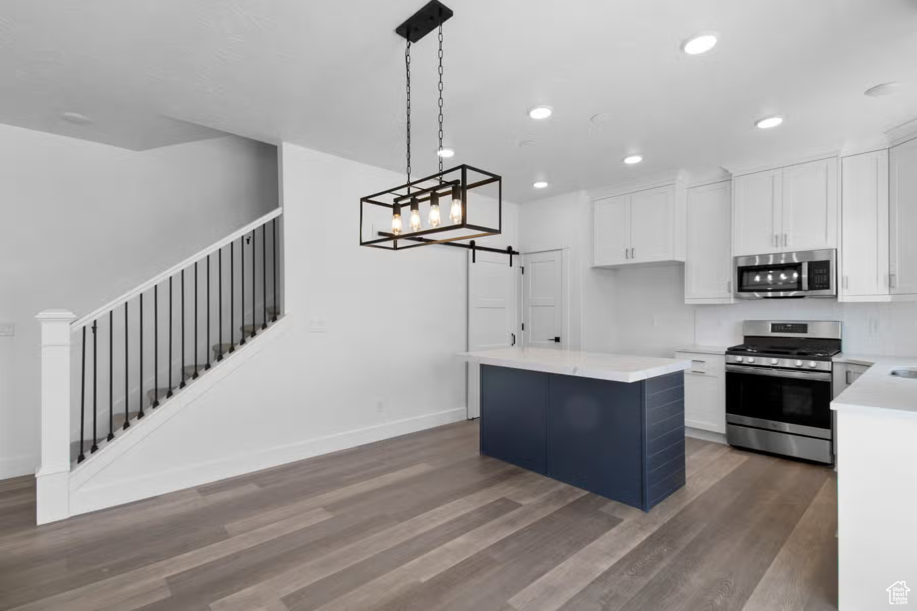 Kitchen featuring a kitchen island, appliances with stainless steel finishes, dark hardwood / wood-style flooring, and white cabinets