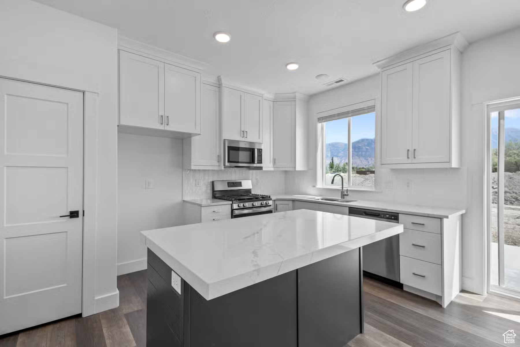 Kitchen featuring appliances with stainless steel finishes, plenty of natural light, hardwood / wood-style flooring, and white cabinetry