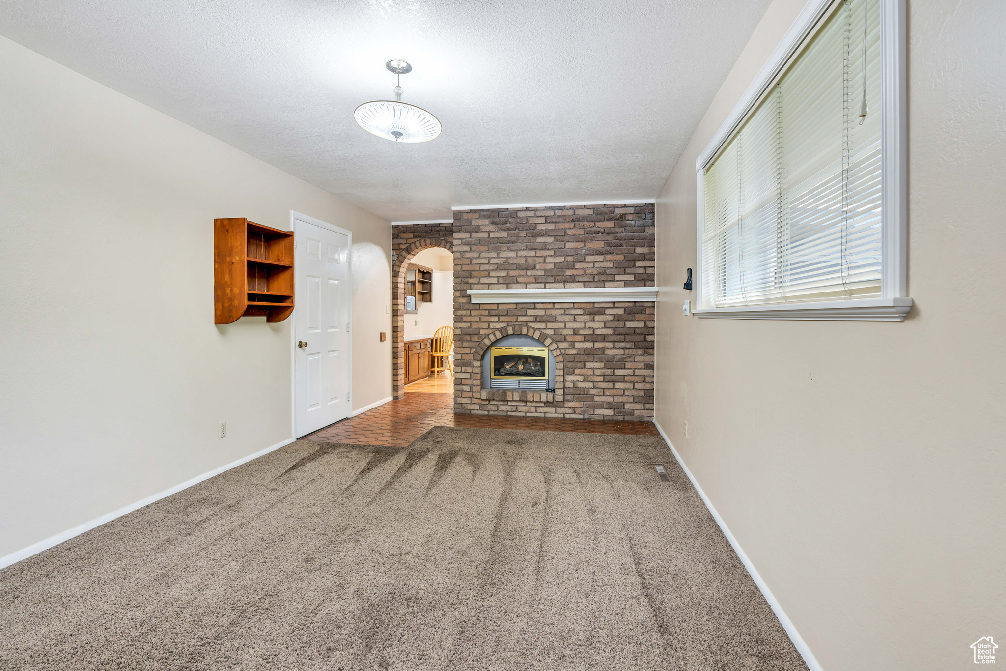 Bonus Den  featuring brick wall, a fireplace, and cozy carpet floors