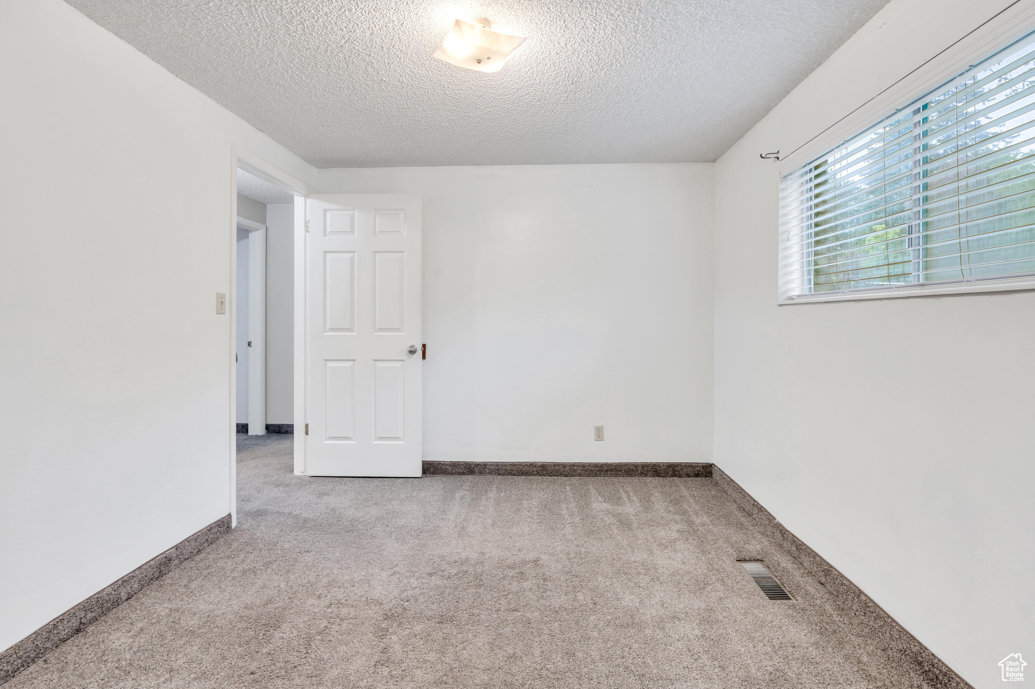 Carpeted bedroom featuring a textured ceiling, new carpet