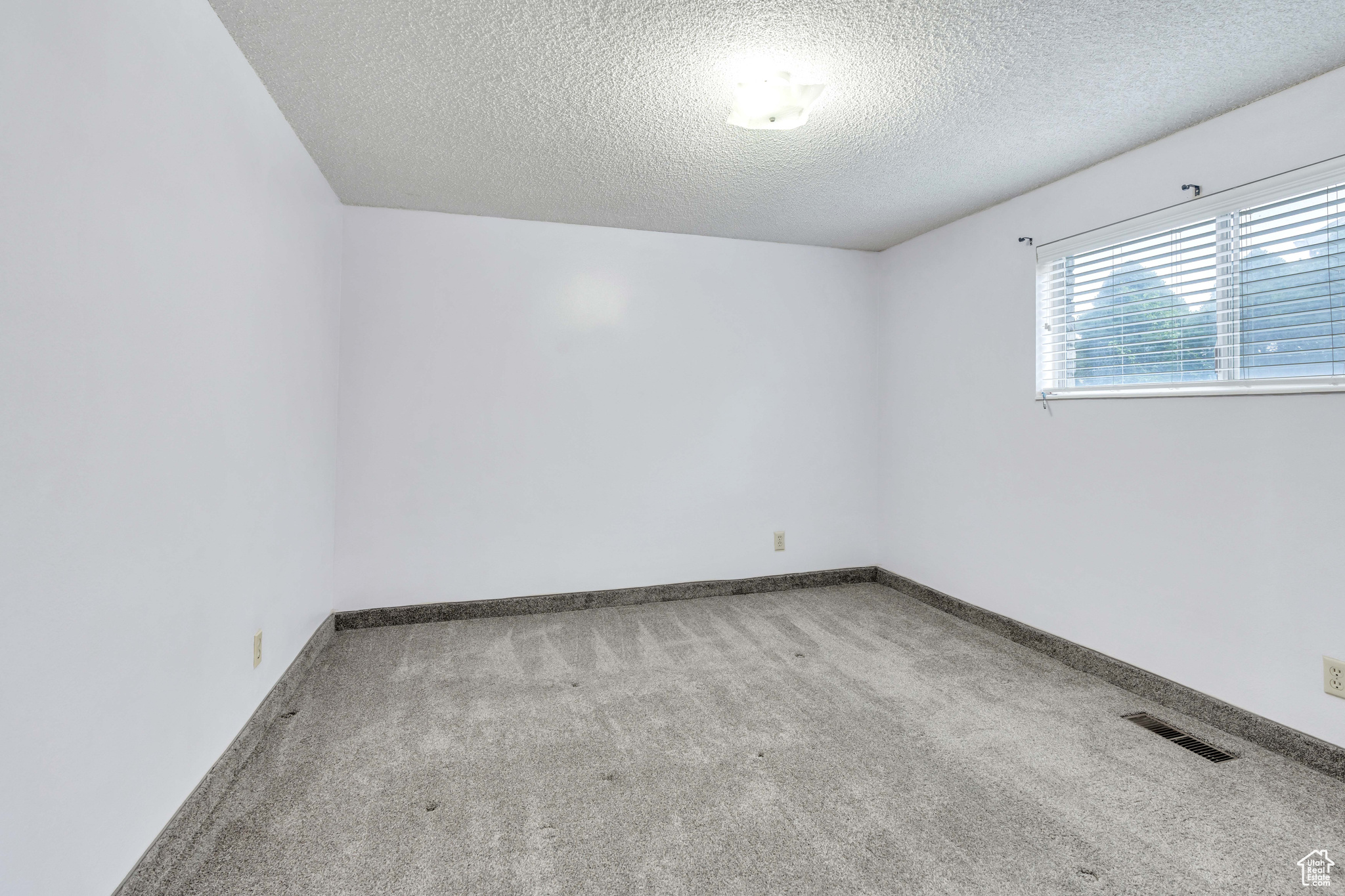 large newly carpeted spare room featuring a textured ceiling and light lavender paint