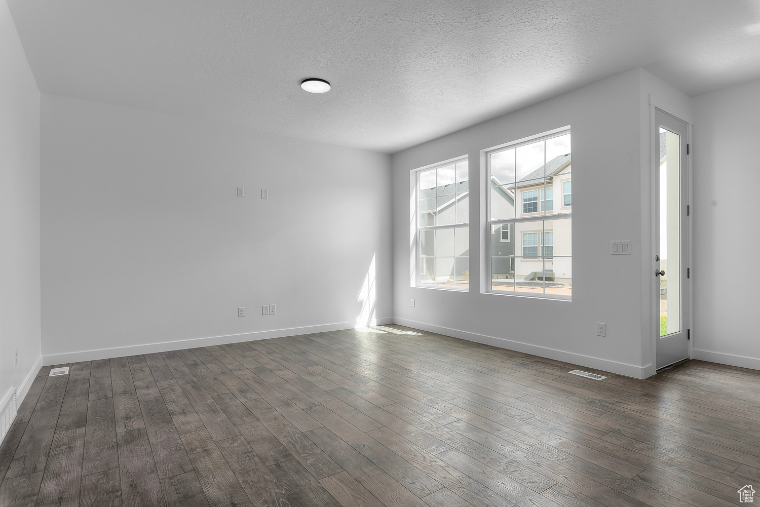 Unfurnished room with a textured ceiling and dark wood-type flooring