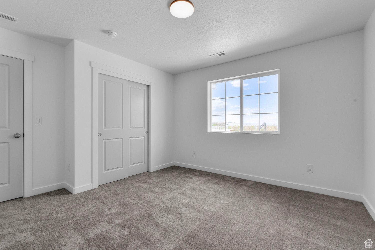 Unfurnished bedroom with a textured ceiling and carpet flooring
