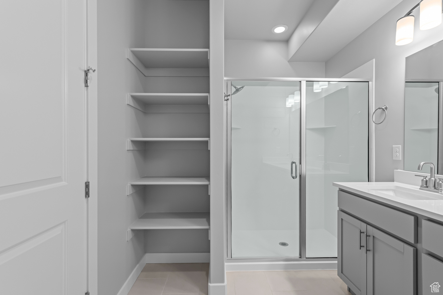 Bathroom with vanity with extensive cabinet space, an enclosed shower, and tile floors