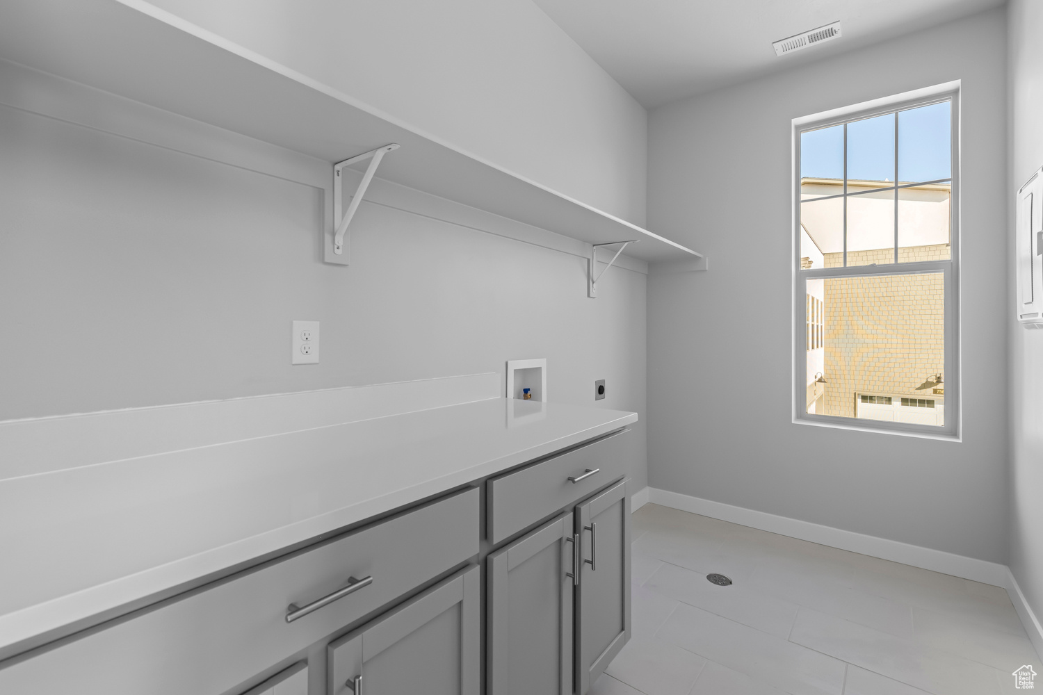 Laundry area featuring plenty of natural light, hookup for a washing machine, hookup for an electric dryer, and light tile flooring