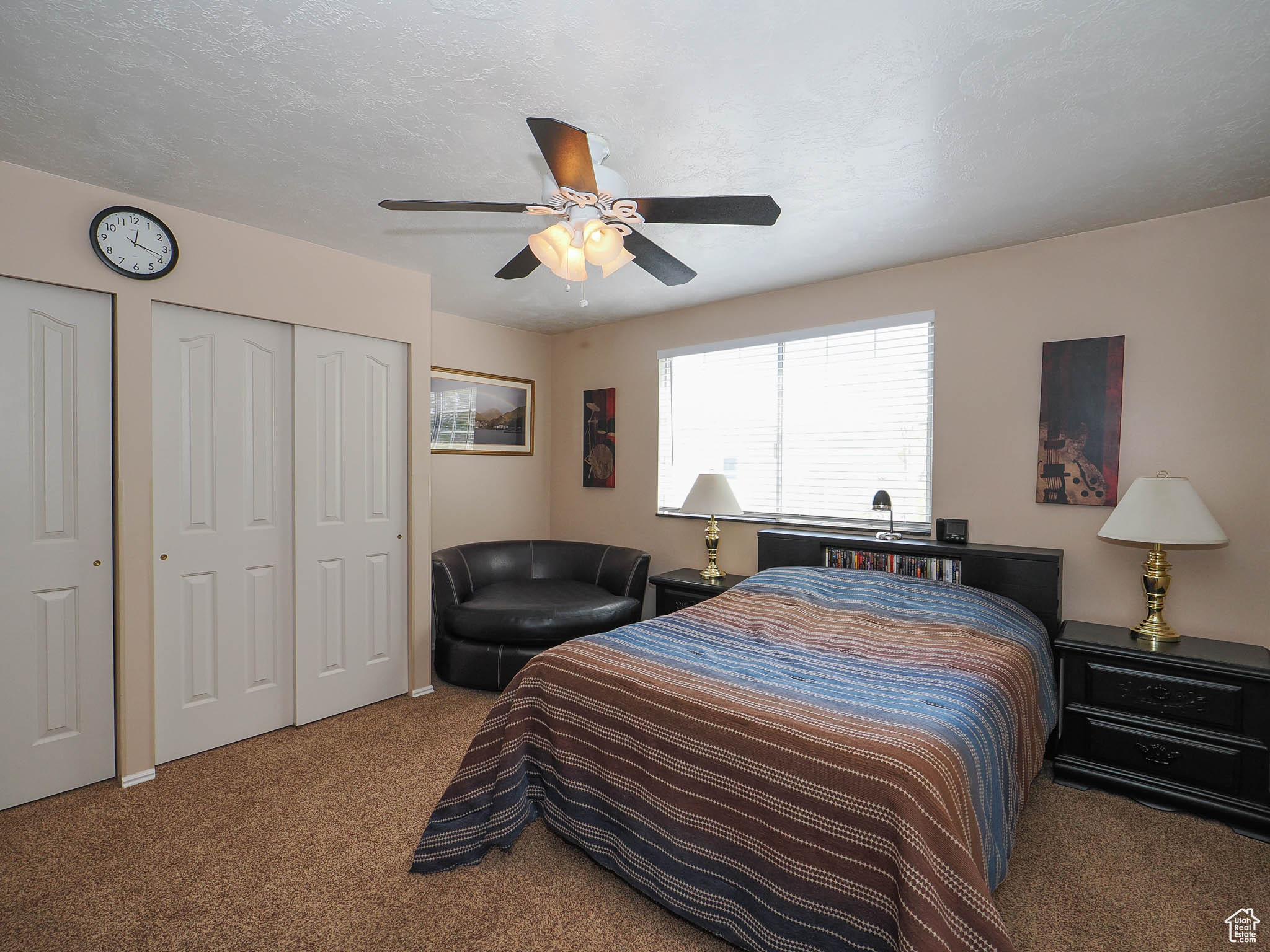 Carpeted bedroom featuring ceiling fan and multiple closets
