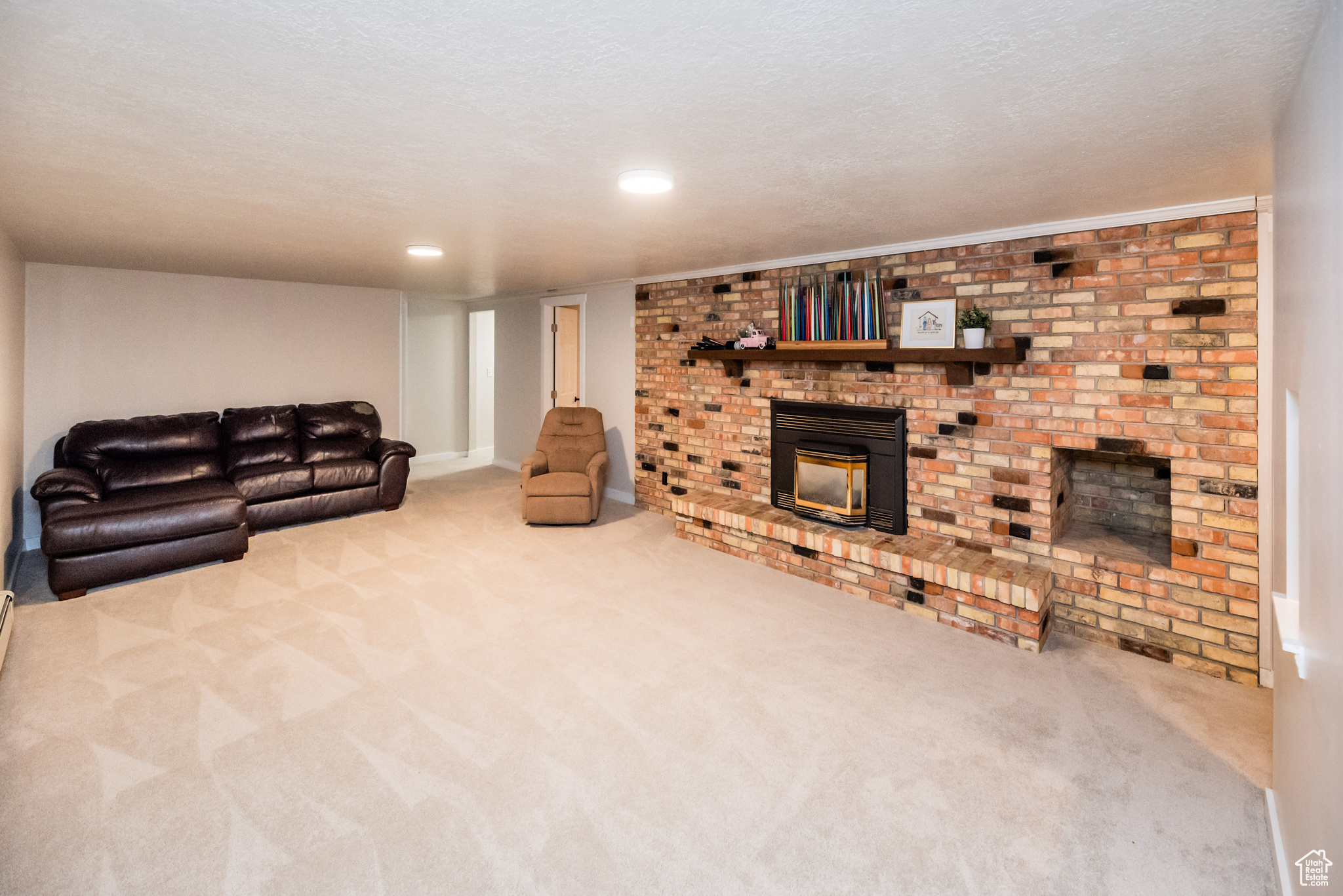 Living room featuring a textured ceiling, carpet, and a brick fireplace