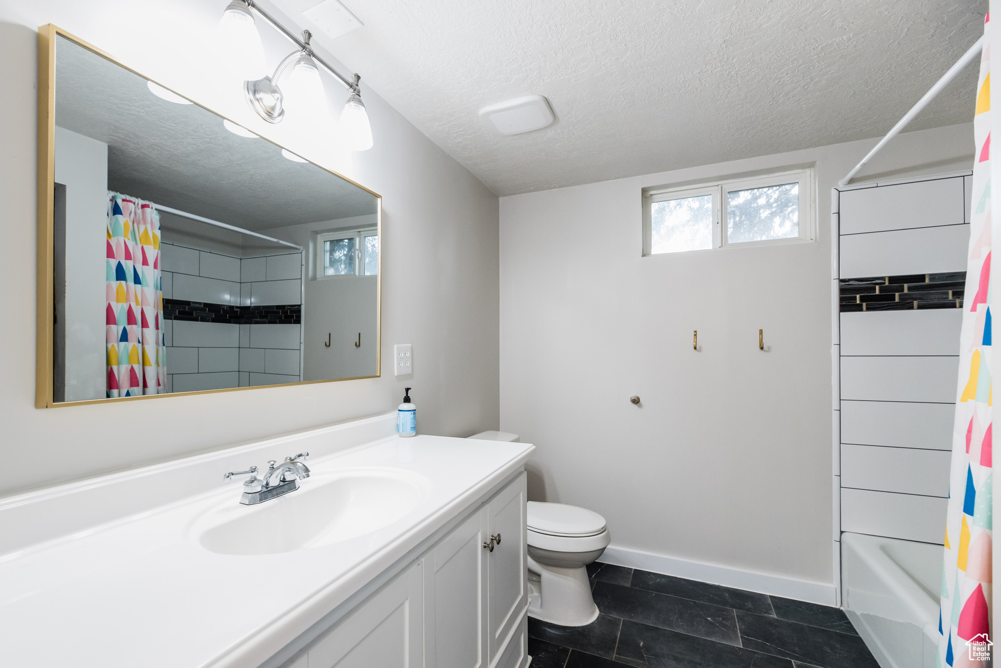 Full bathroom featuring a textured ceiling, shower / tub combo with curtain, tile floors, toilet, and vanity