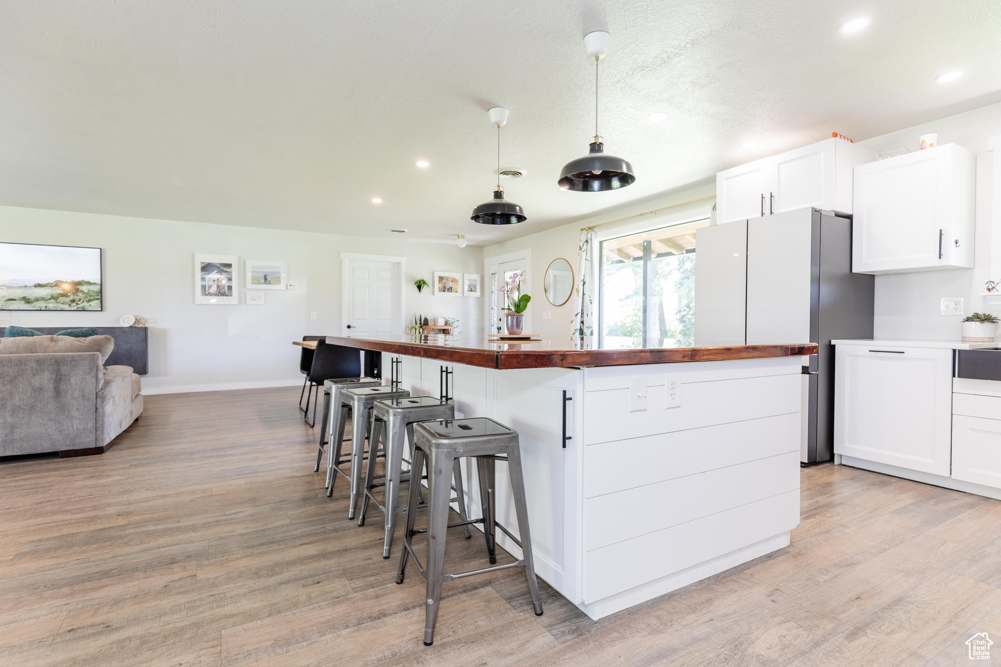 Kitchen featuring wooden counters, pendant lighting, light hardwood / wood-style floors, and white cabinetry