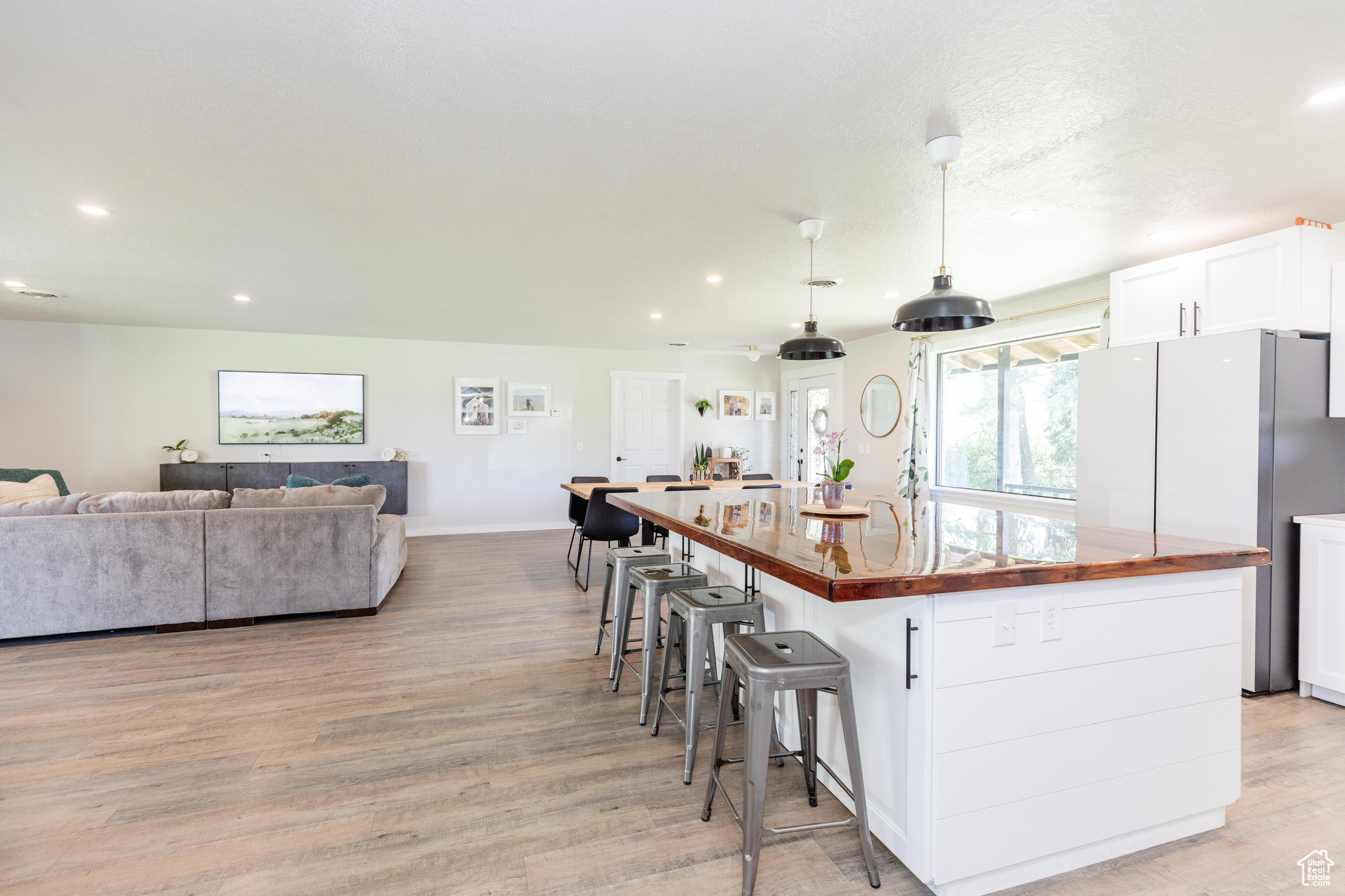 Kitchen featuring butcher block countertops, light hardwood / wood-style floors, white cabinetry, and an island with sink