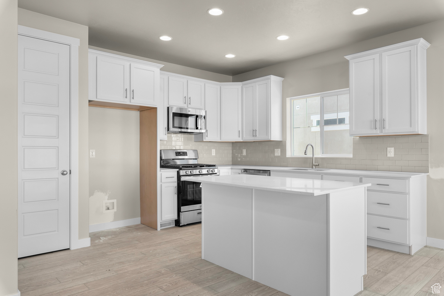 Kitchen with white cabinets, a center island, and stainless steel appliances