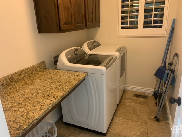 Clothes washing area with cabinets, independent washer and dryer, tile floors, and hookup for a washing machine