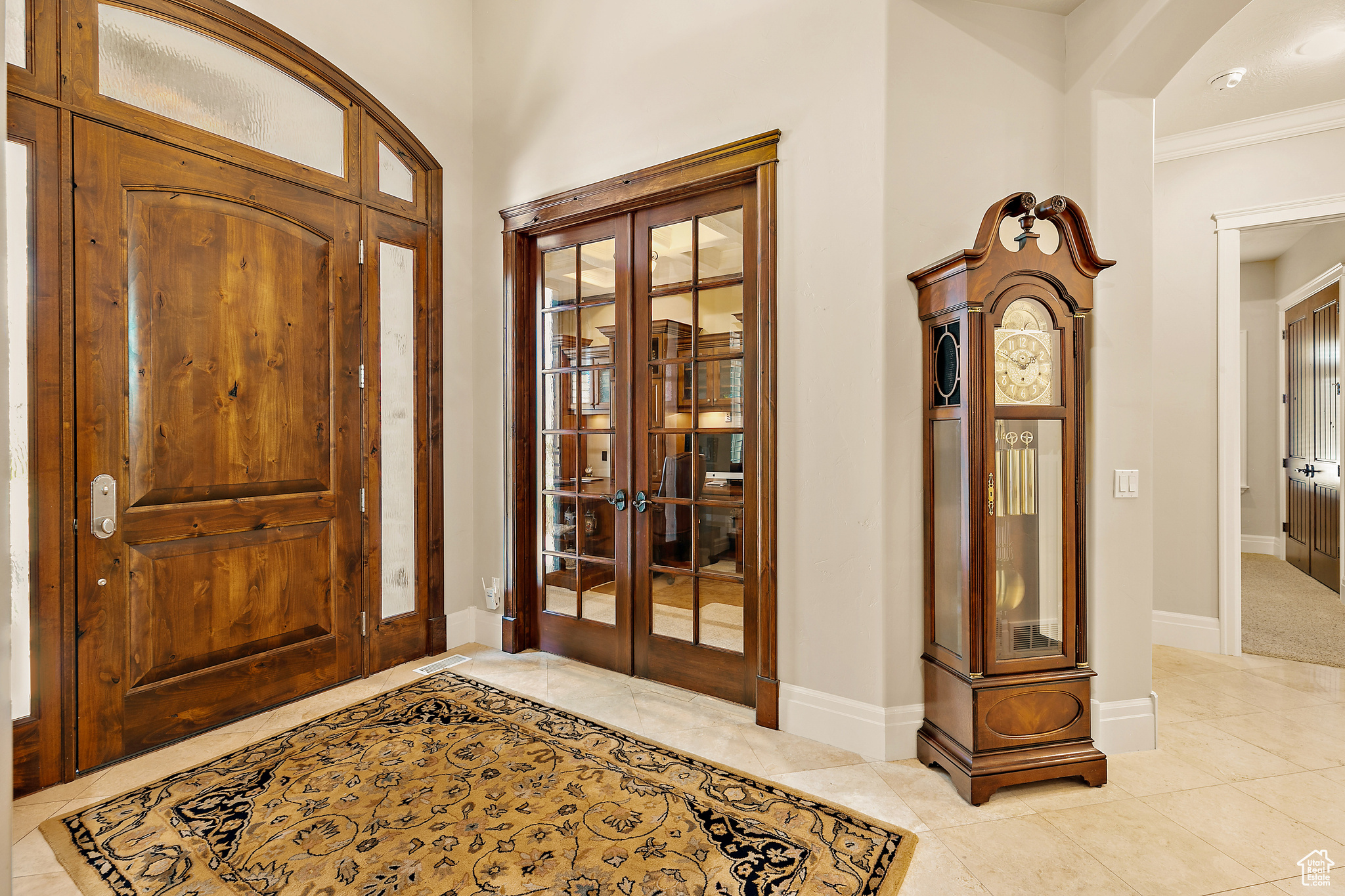 Entrance foyer featuring french doors, crown molding, and light tile floors