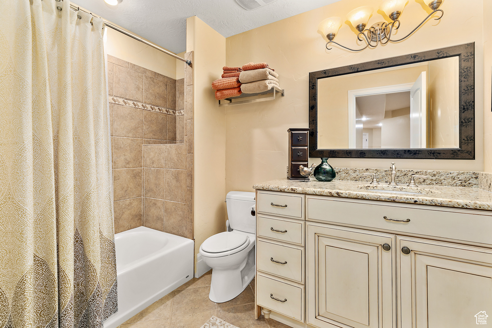 Full bathroom featuring shower / bath combo with shower curtain, a textured ceiling, tile floors, toilet, and vanity