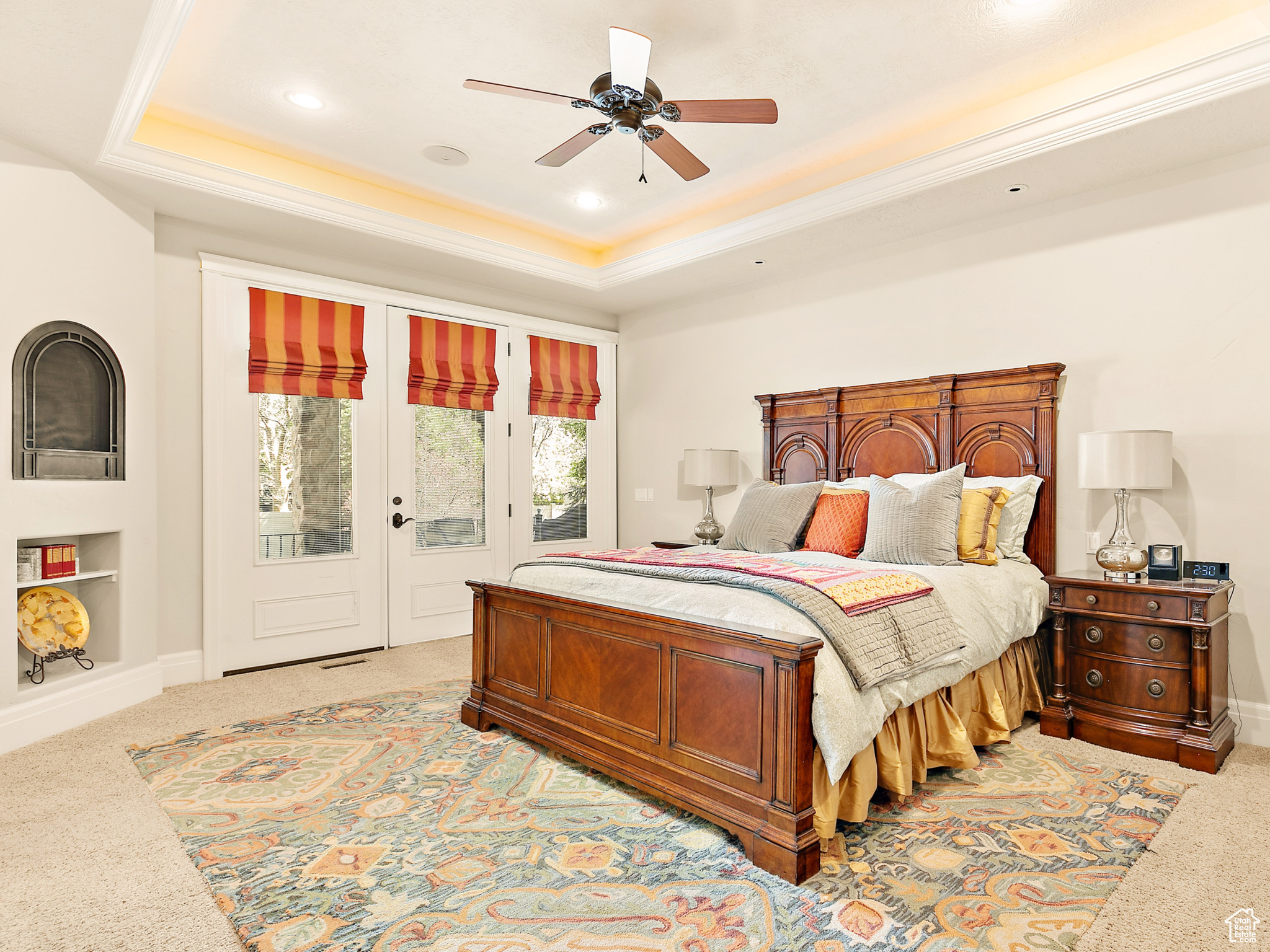 Bedroom featuring ceiling fan, carpet flooring, a raised ceiling, and access to exterior