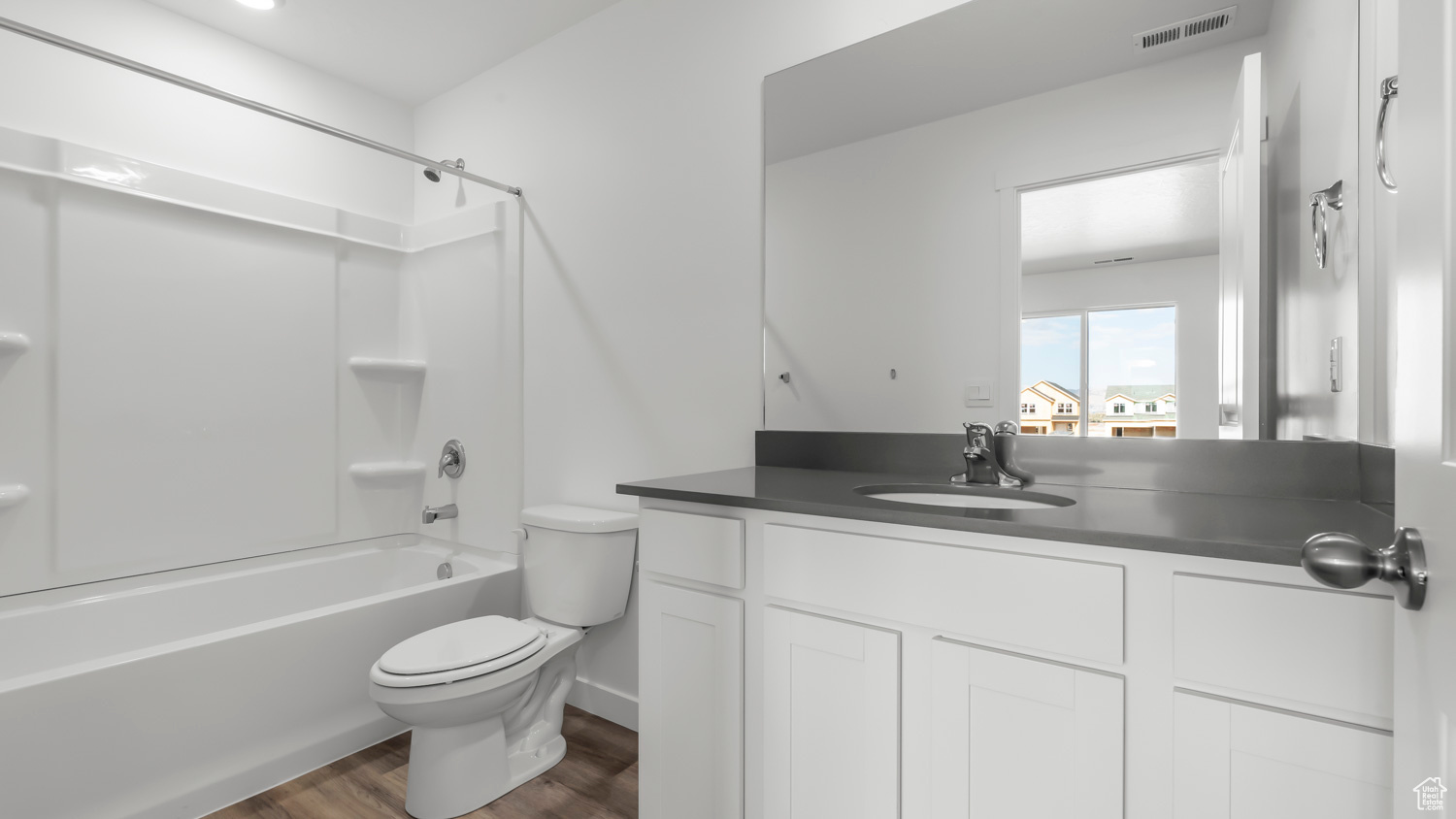 Full bathroom with hardwood / wood-style flooring, toilet, shower / washtub combination, and vanity