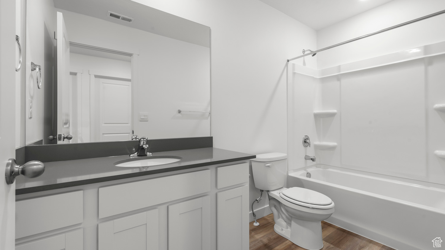 Full bathroom with hardwood / wood-style floors, oversized vanity, shower / washtub combination, and toilet