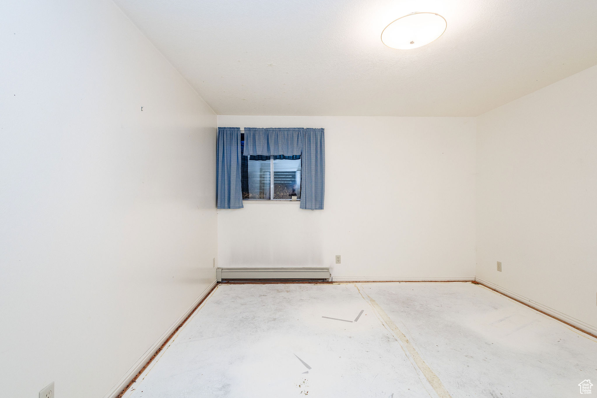 Unfurnished room with a baseboard heating unit