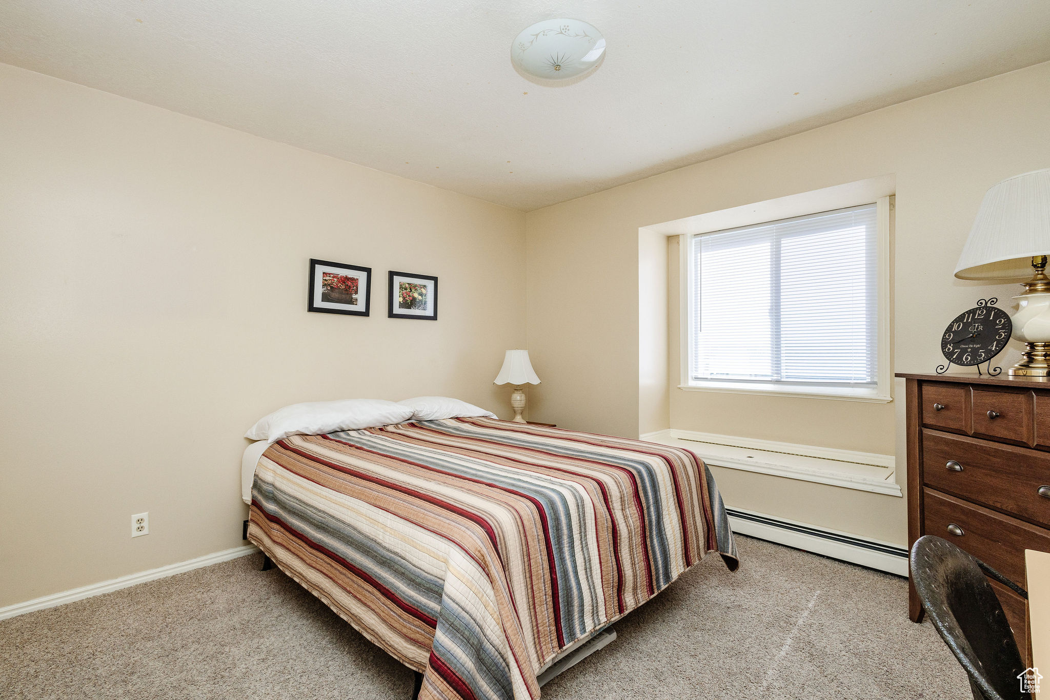 Carpeted bedroom with a baseboard heating unit