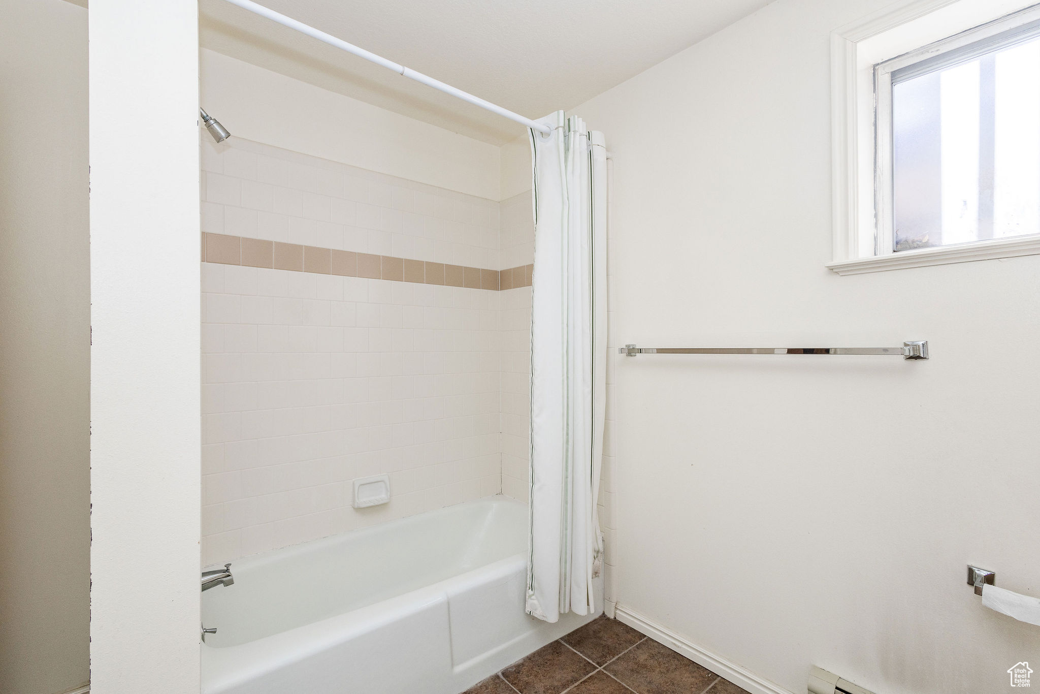 Bathroom featuring baseboard heating, tile floors, and shower / tub combo with curtain