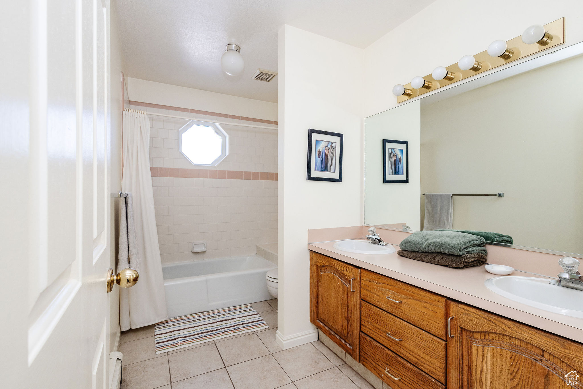 Full bathroom featuring shower / tub combo, toilet, double vanity, and tile flooring