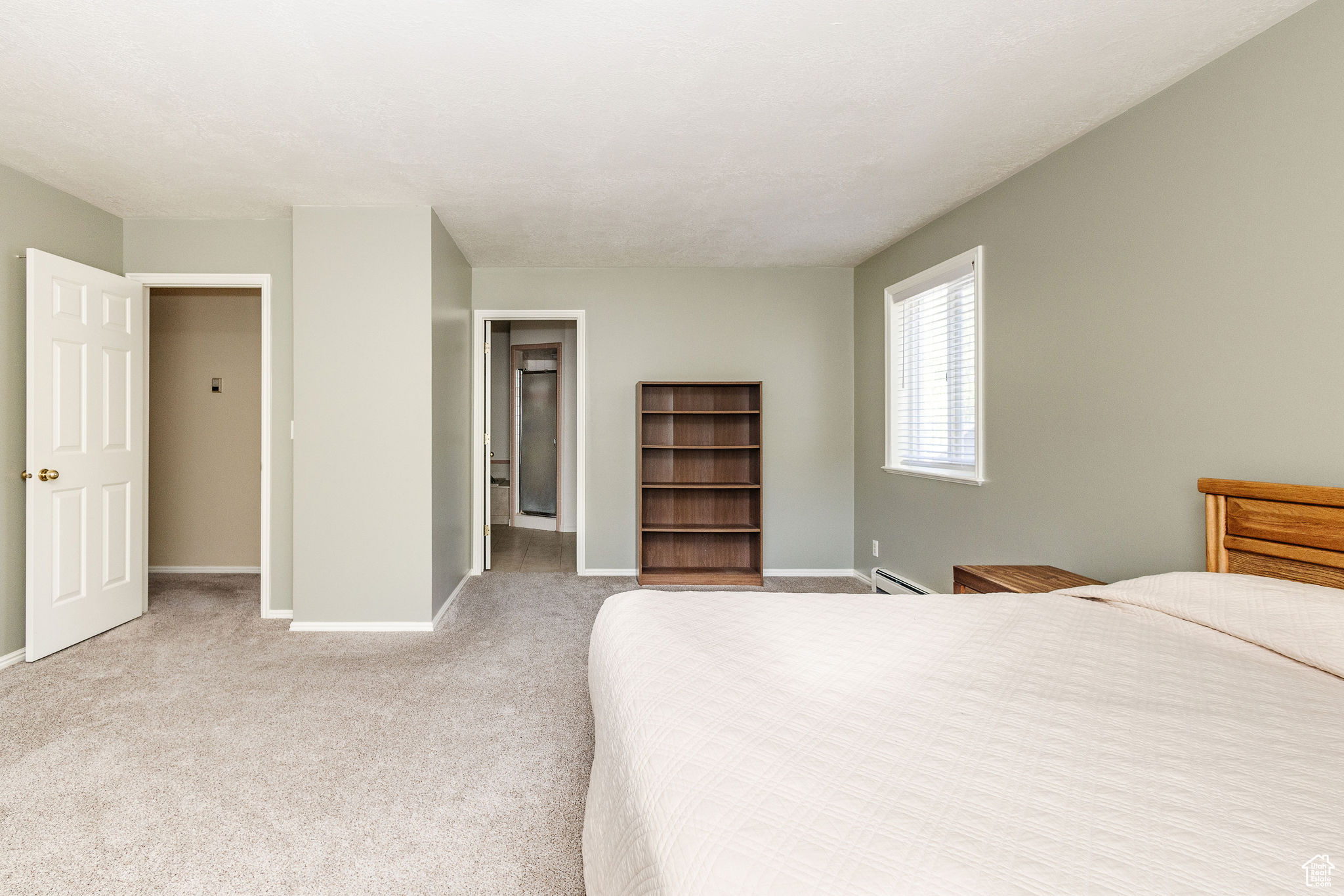 Bedroom featuring light carpet and baseboard heating