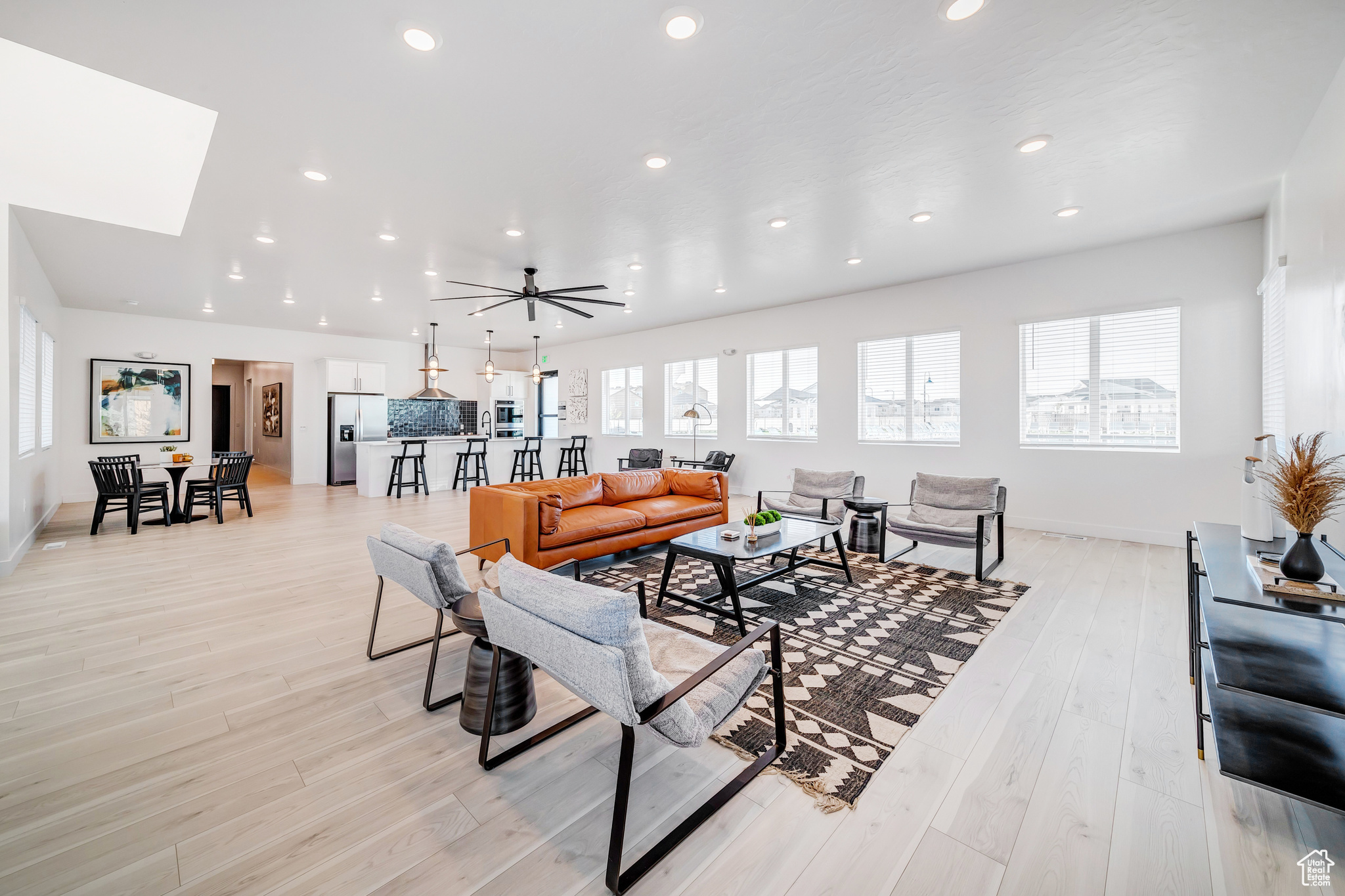 Living room featuring a skylight, light hardwood / wood-style floors, and ceiling fan