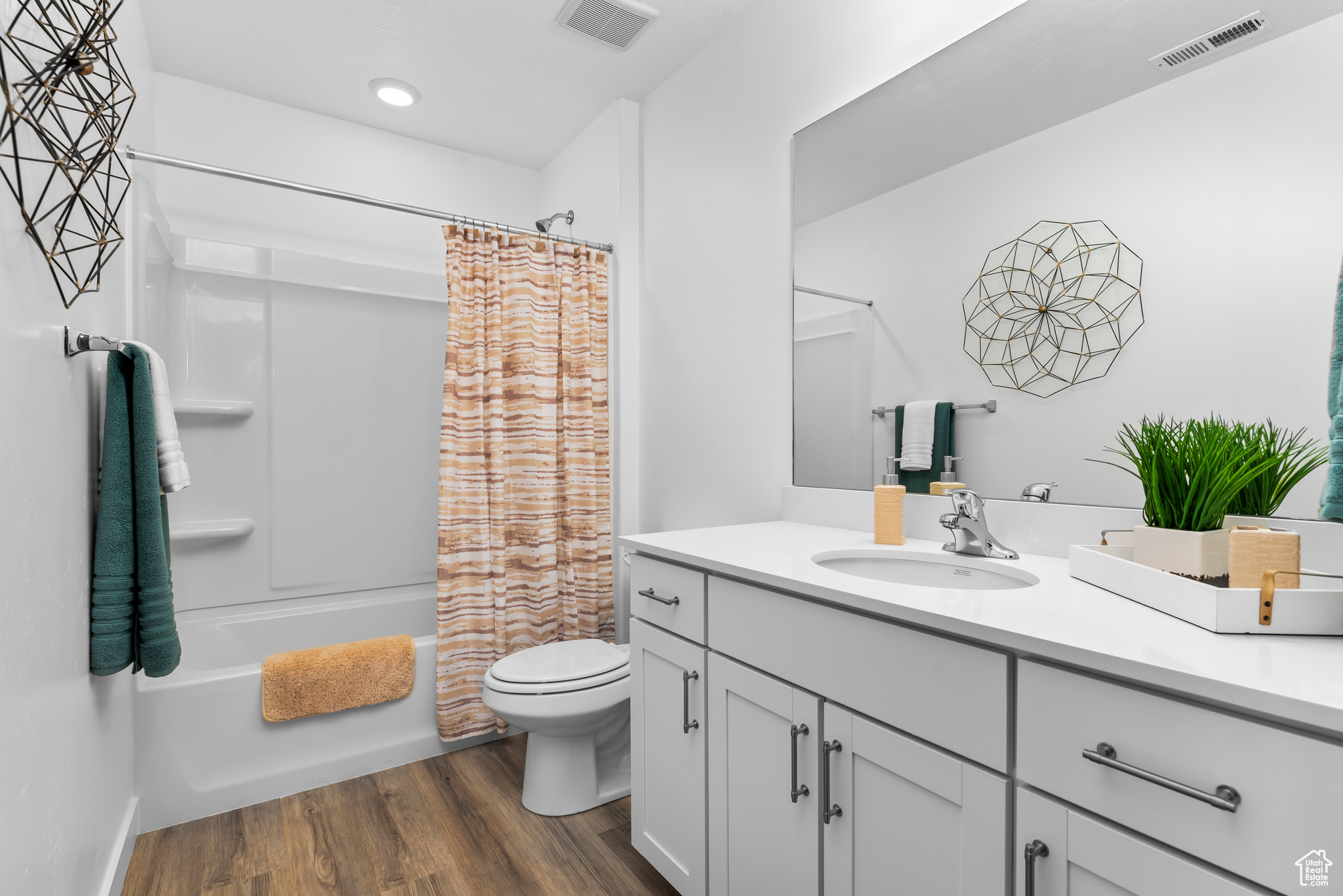 Full bathroom featuring hardwood / wood-style flooring, shower / bath combo, vanity, and toilet