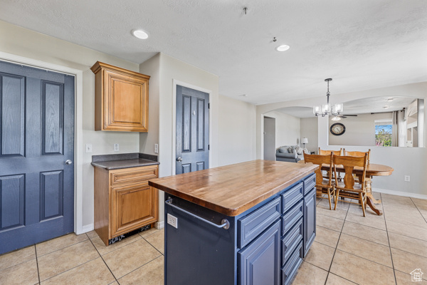 Kitchen with a center island, light tile floors, butcher block counterto!