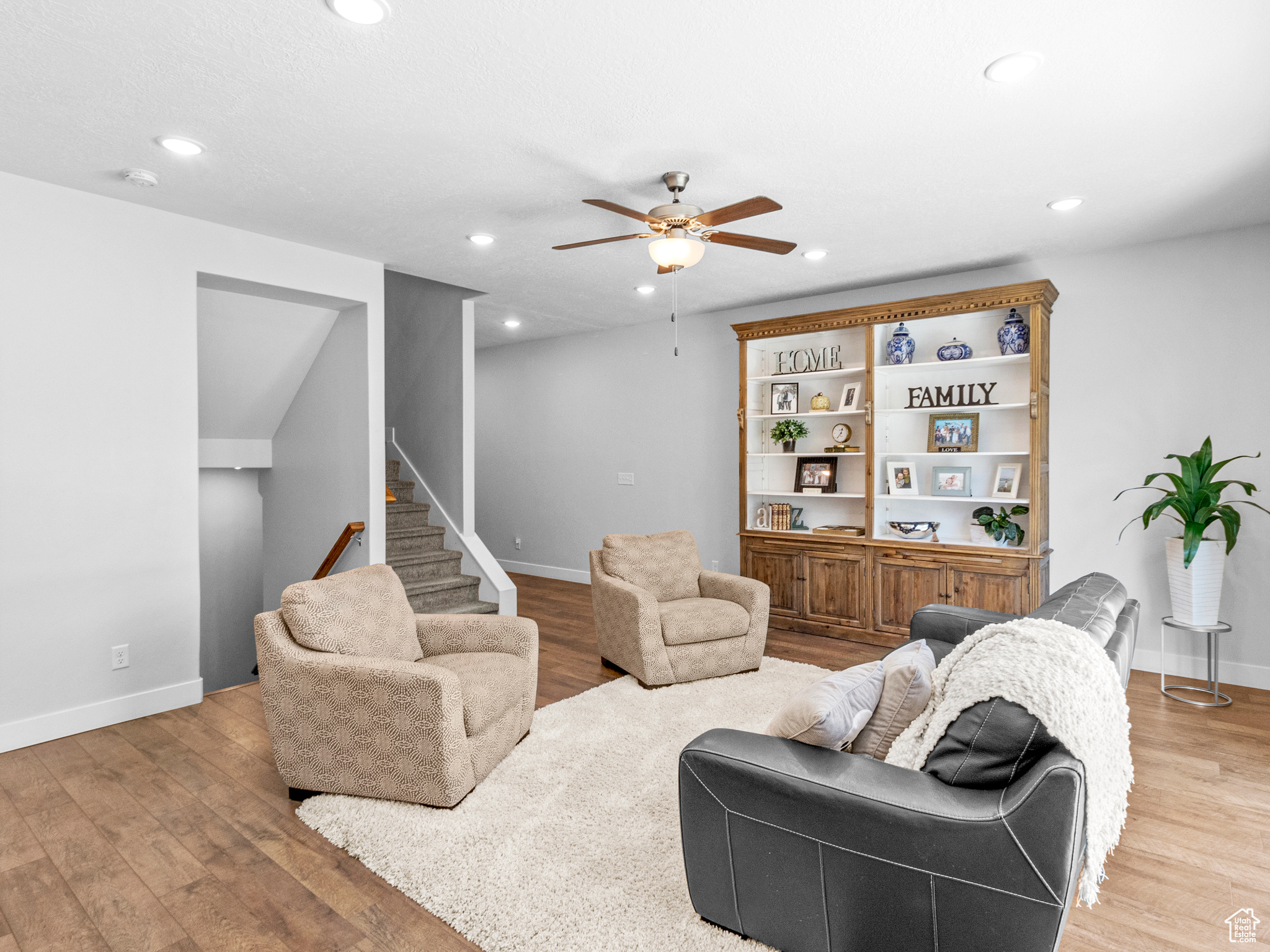 Living room with built in features, wood-type flooring, and ceiling fan