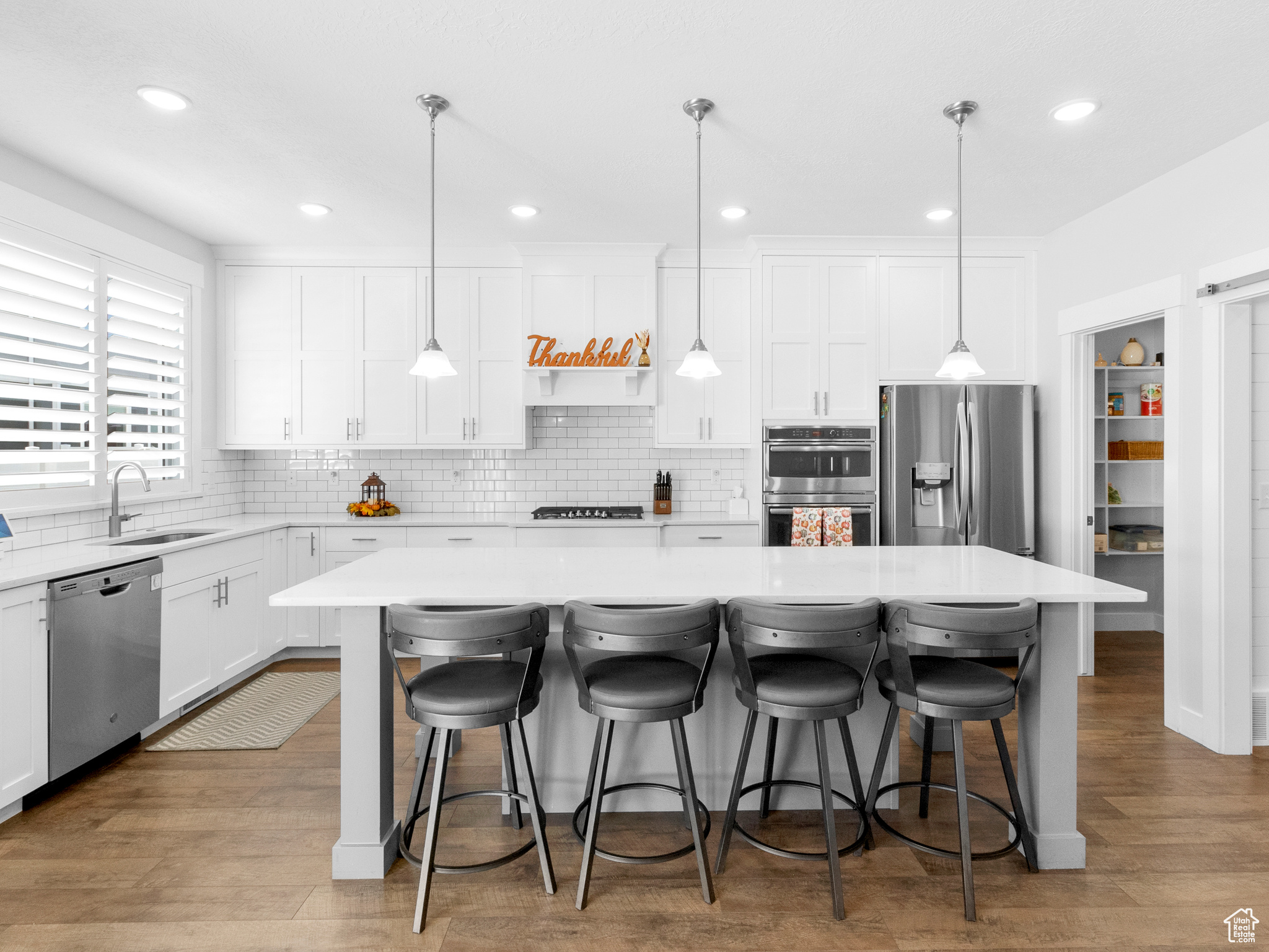 Kitchen with a kitchen bar, appliances with stainless steel finishes, light hardwood / wood-style flooring, tasteful backsplash, and a center island