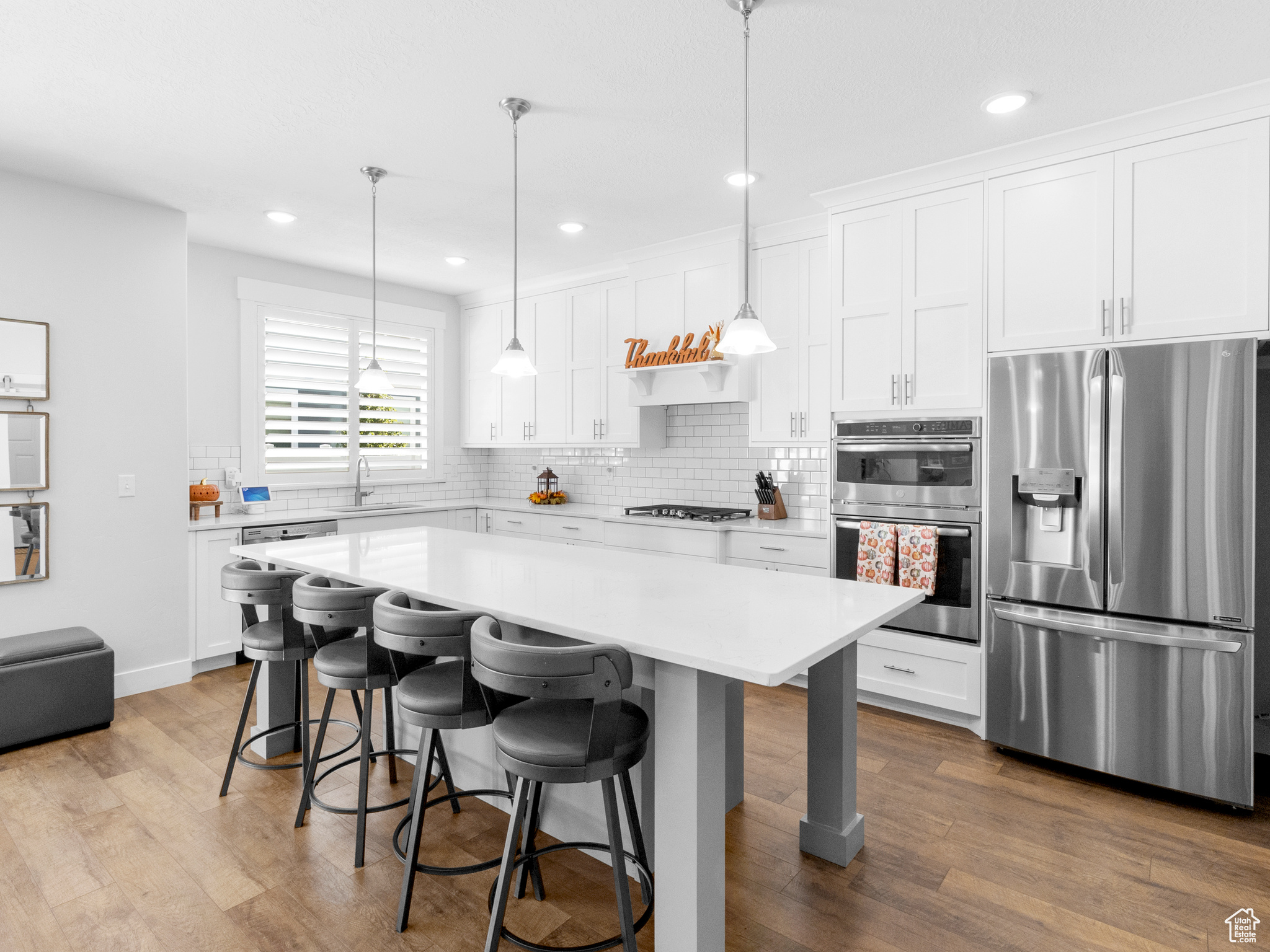 Kitchen featuring a kitchen island, stainless steel appliances, white cabinets, and hardwood / wood-style floors