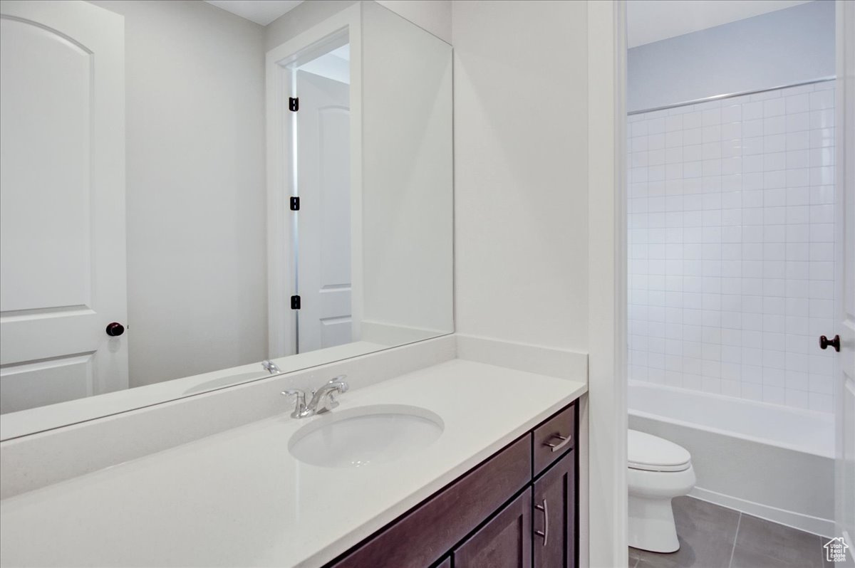 Full bathroom featuring tile flooring,  shower combination, vanity with extensive cabinet space, and toilet
