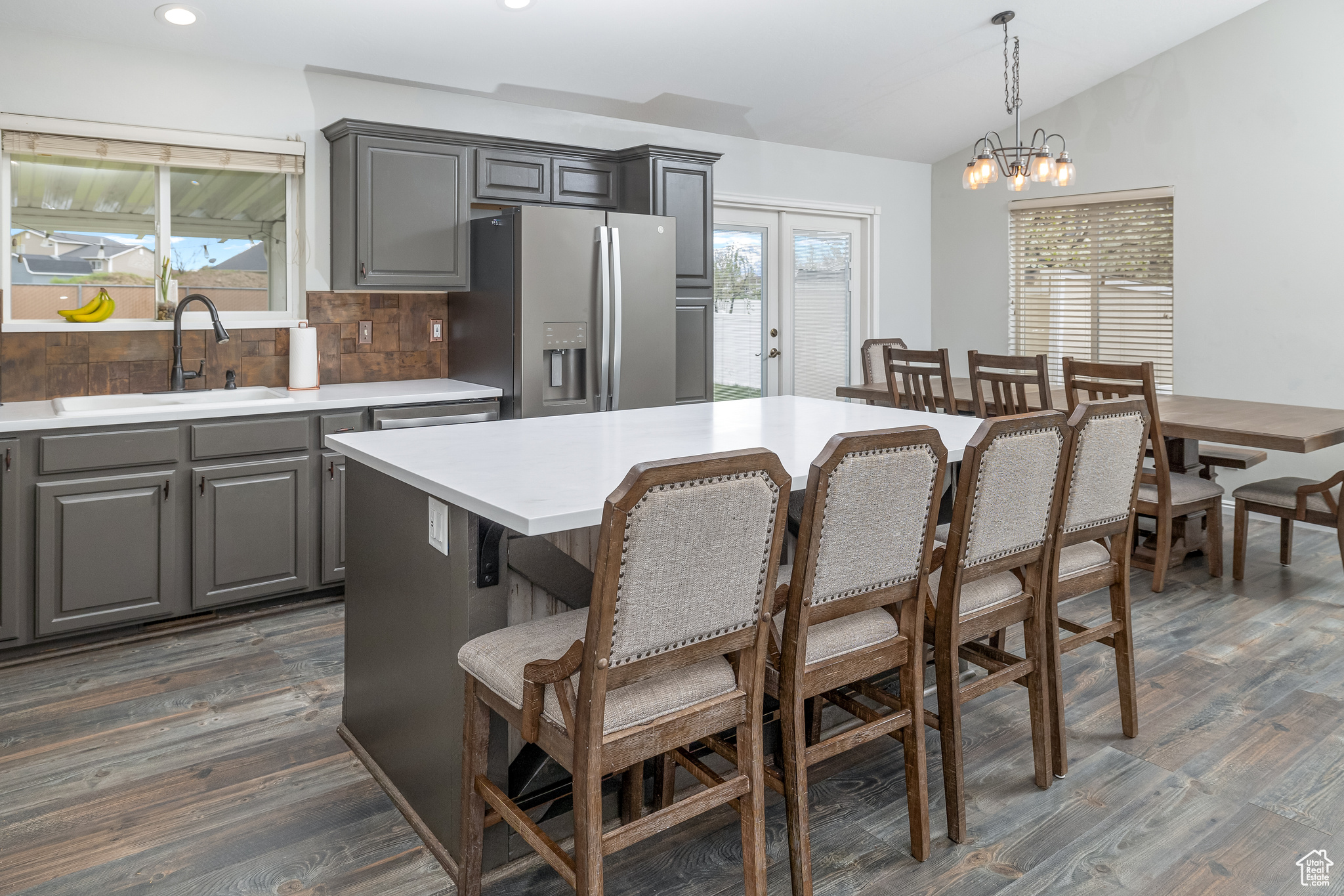 Kitchen with pendant lighting, stainless steel fridge with ice dispenser, backsplash, sink, and dark hardwood / wood-style flooring