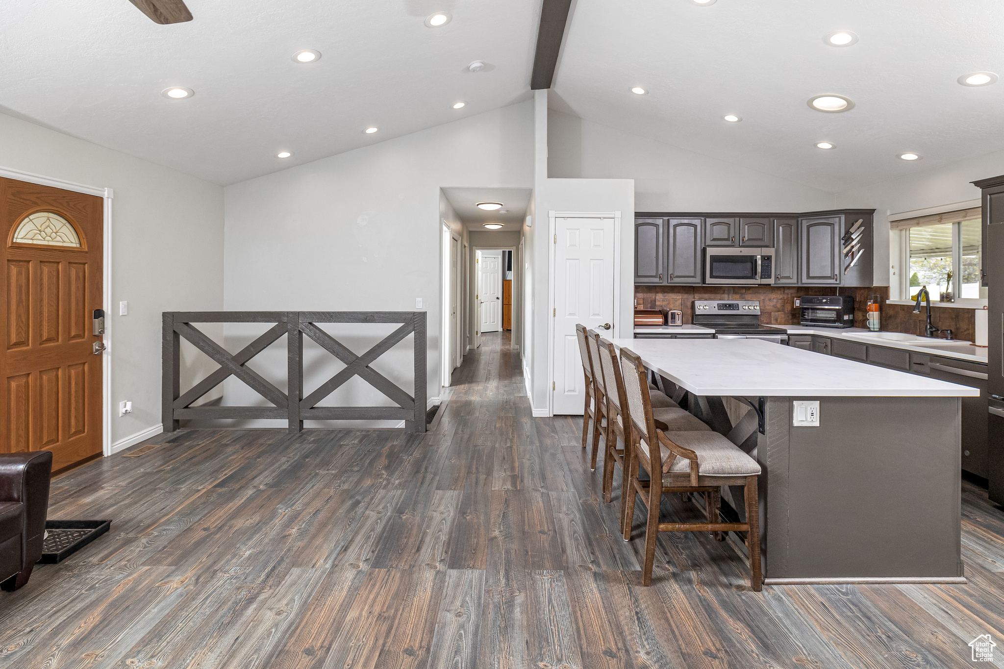 Kitchen with a center island, beamed ceiling, dark hardwood / wood-style flooring, appliances with stainless steel finishes, and copper backsplash