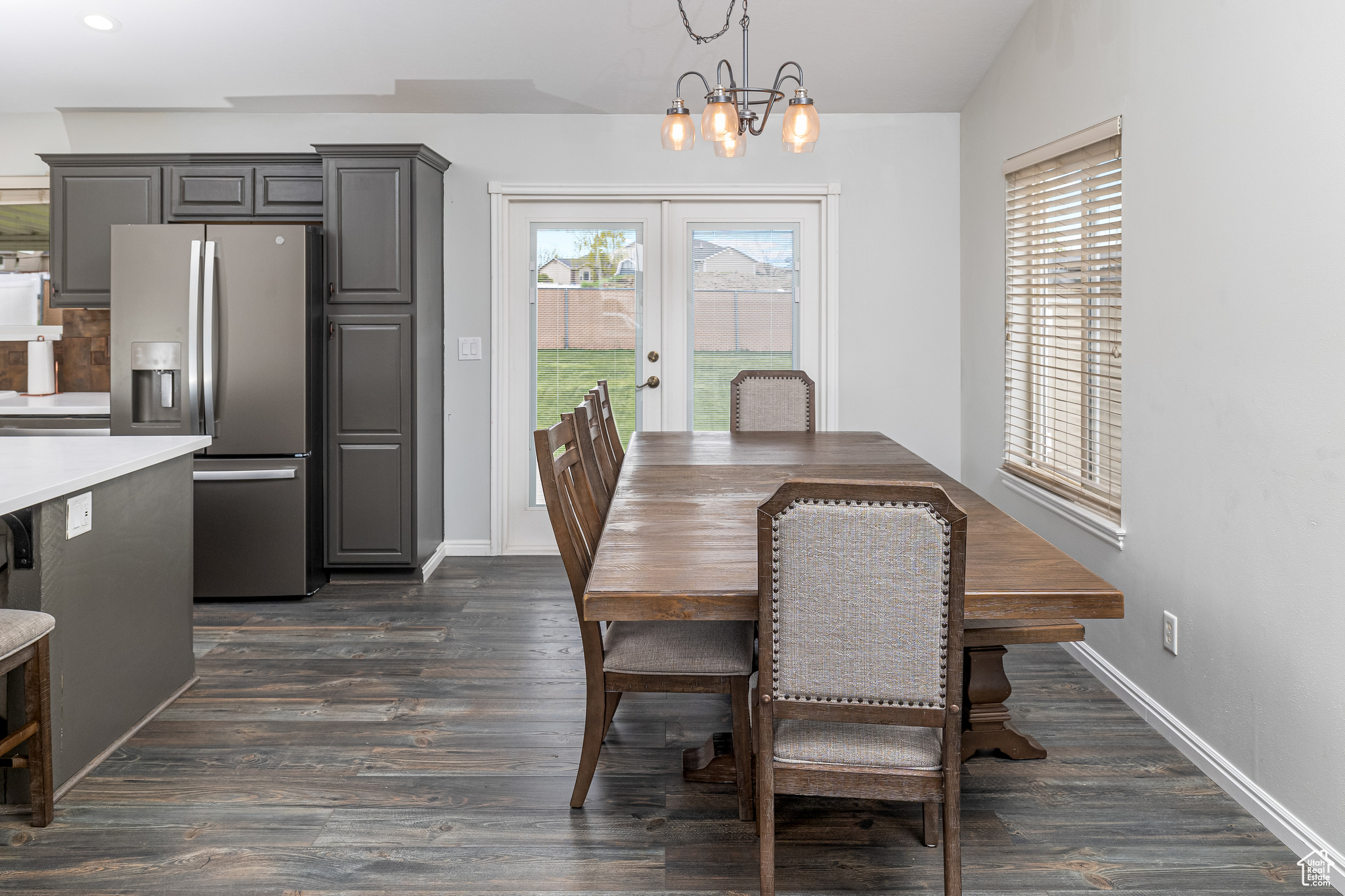 Dining room with a wealth of natural light, dark wood-type flooring, french doors, and a chandelier