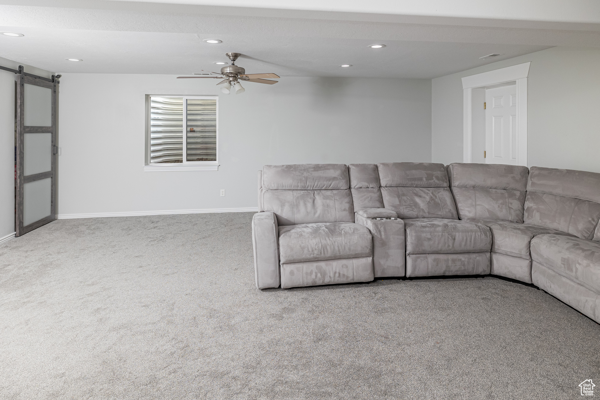 Living room with carpet flooring, a barn door, and ceiling fan