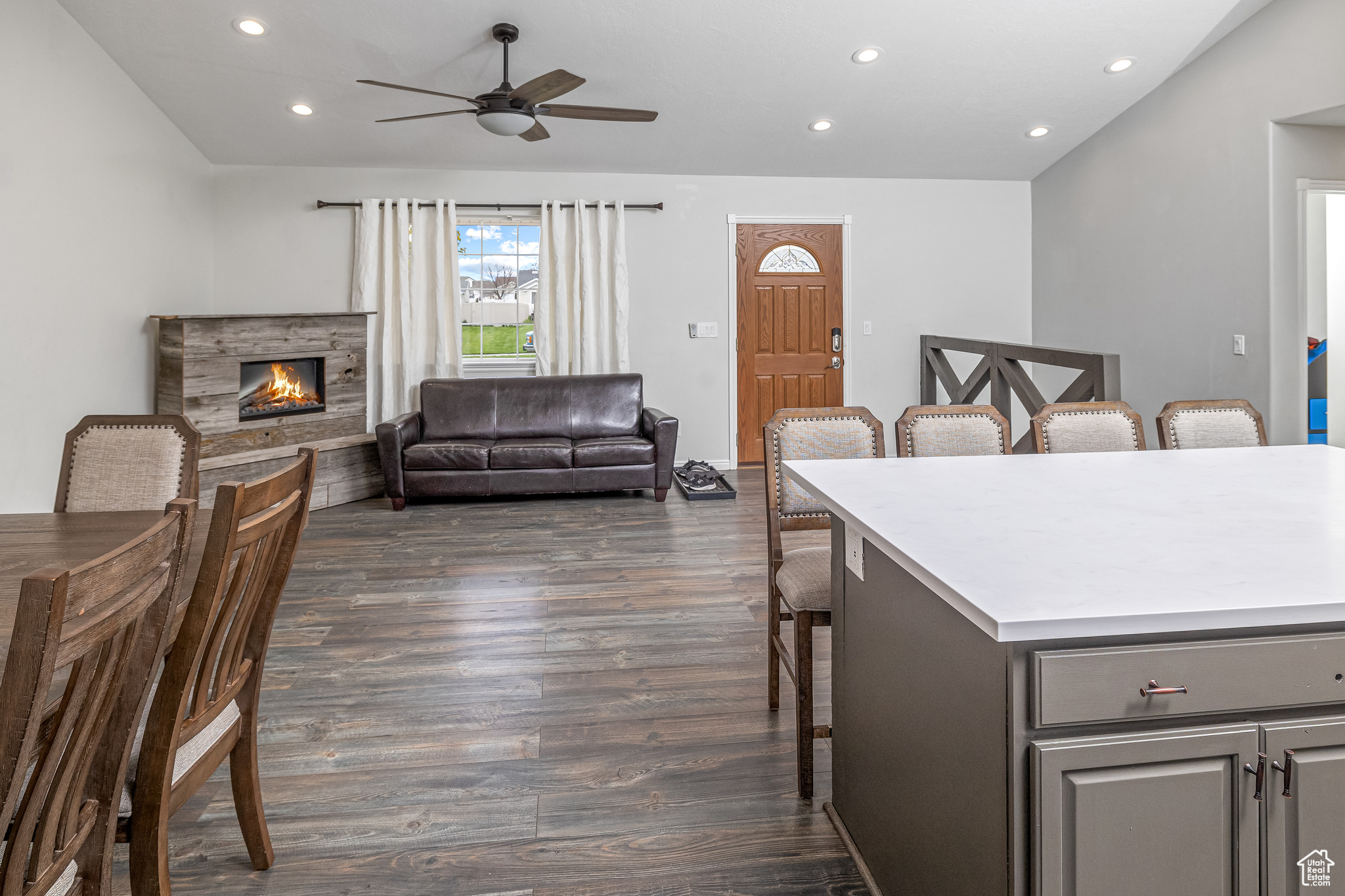 Interior space with ceiling fan, a stone fireplace, a kitchen breakfast bar, and dark hardwood / wood-style floors