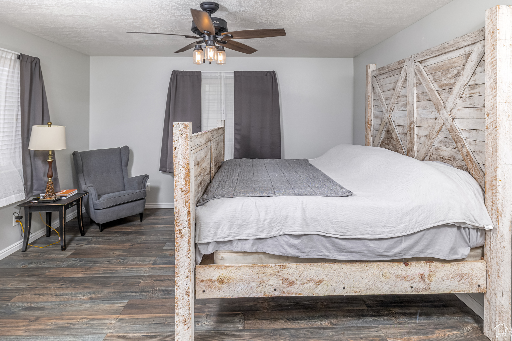 Primary bedroom with dark hardwood / wood-style flooring, ceiling fan, and a textured ceiling