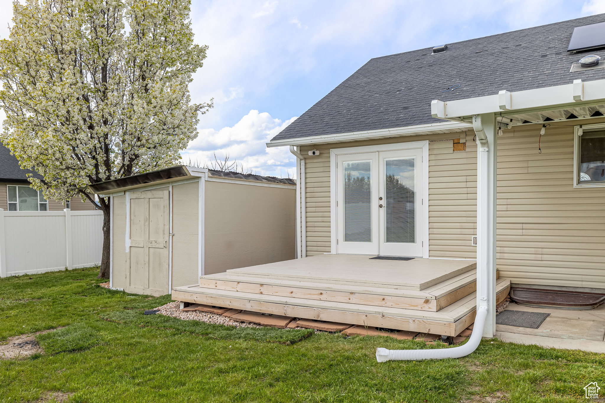 Wooden deck with french doors, an outdoor structure, and a lawn