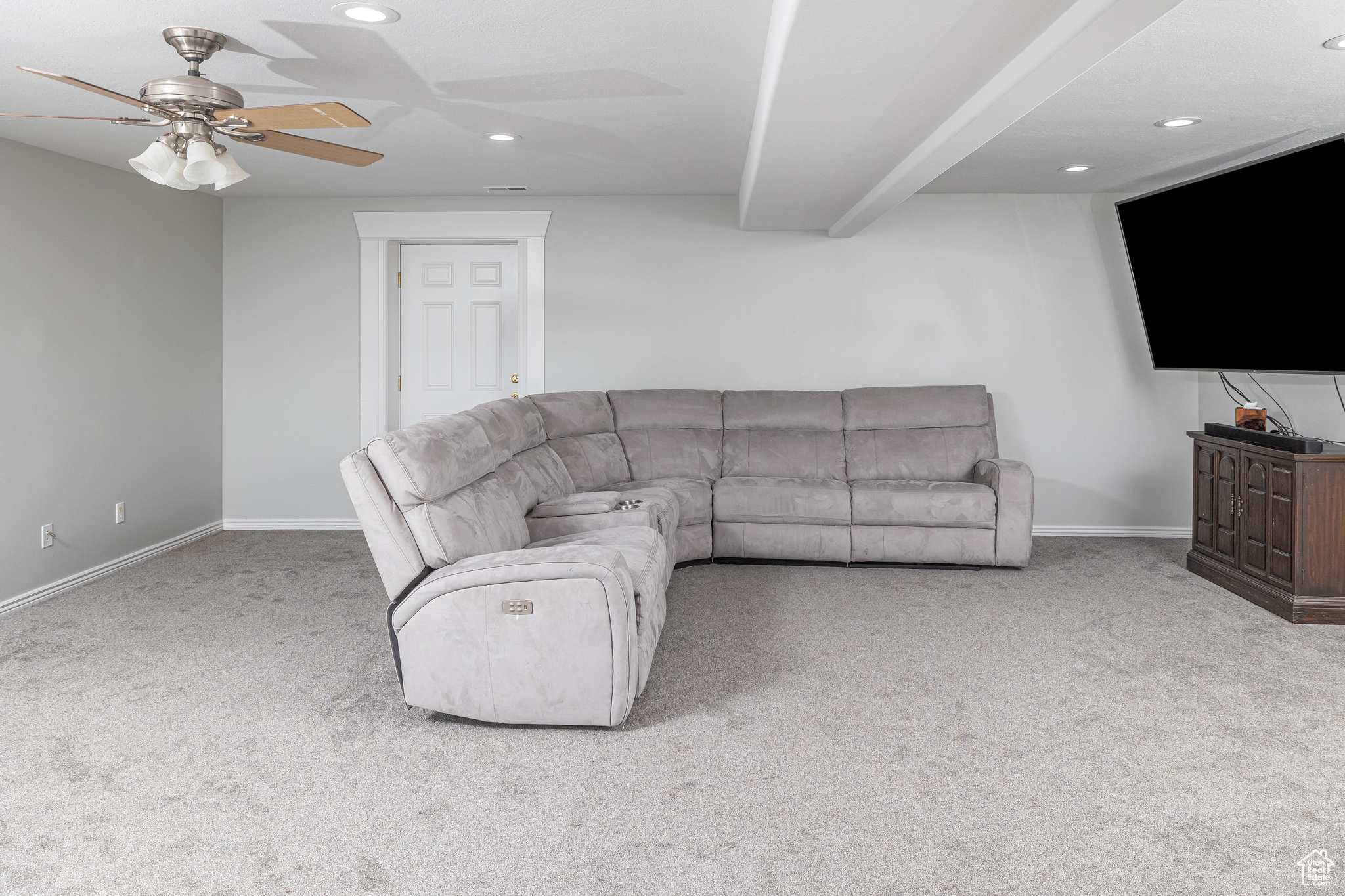 Carpeted living room featuring ceiling fan