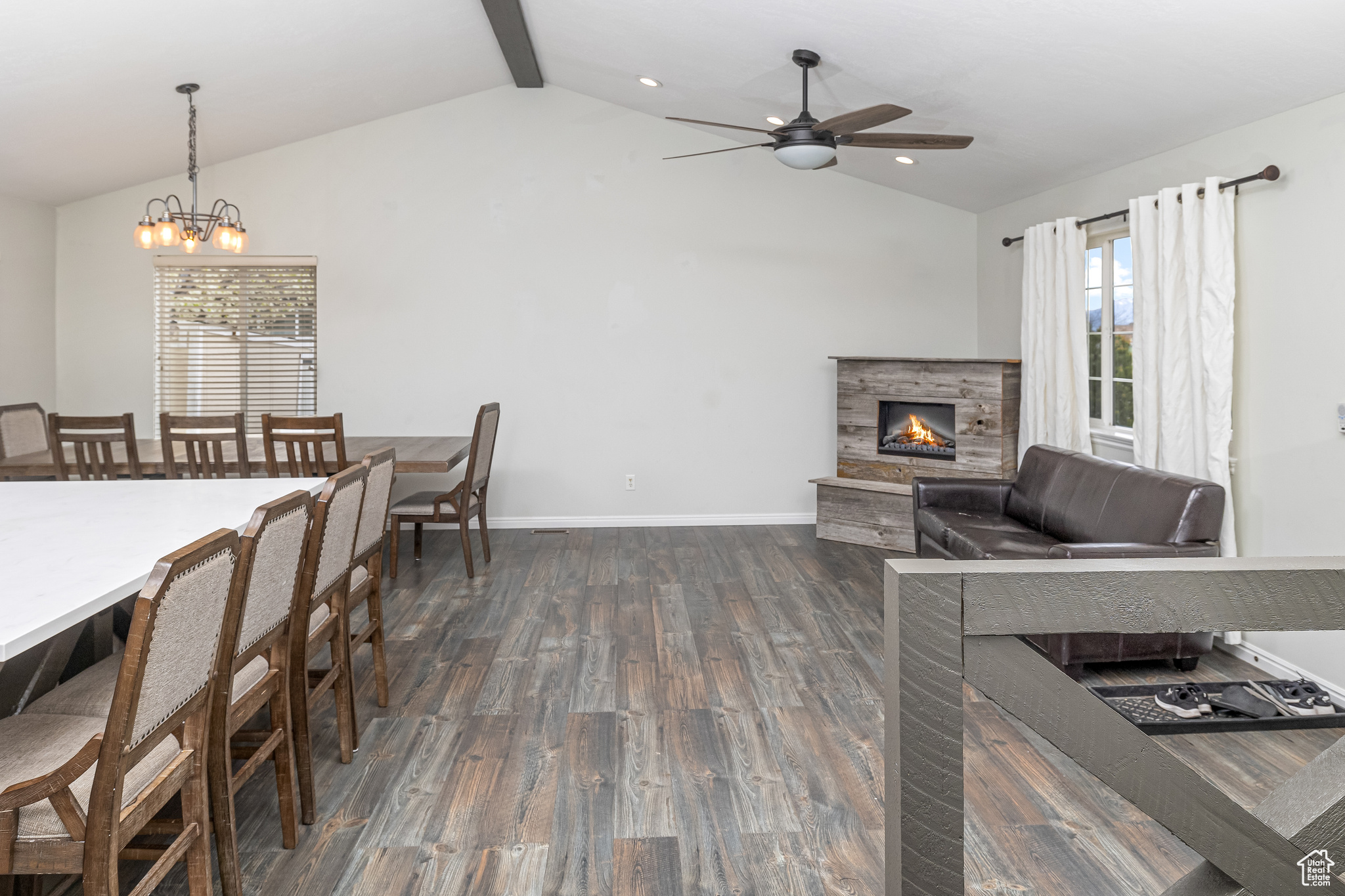 Interior space featuring a wealth of natural light, dark wood-type flooring, vaulted ceiling with beams, and a fireplace