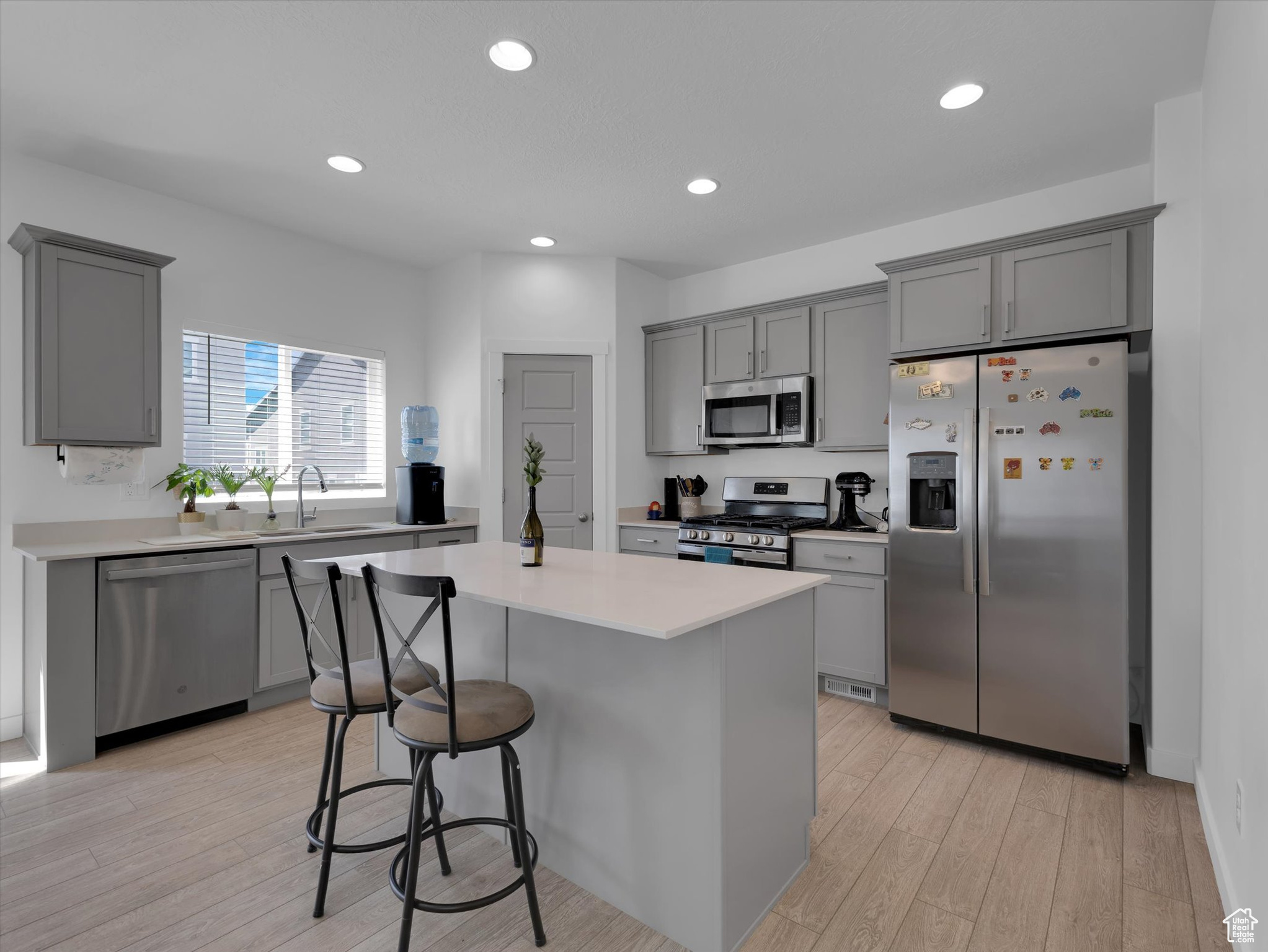 Kitchen featuring a kitchen island, gray cabinetry, appliances with stainless steel finishes, and light wood-type flooring