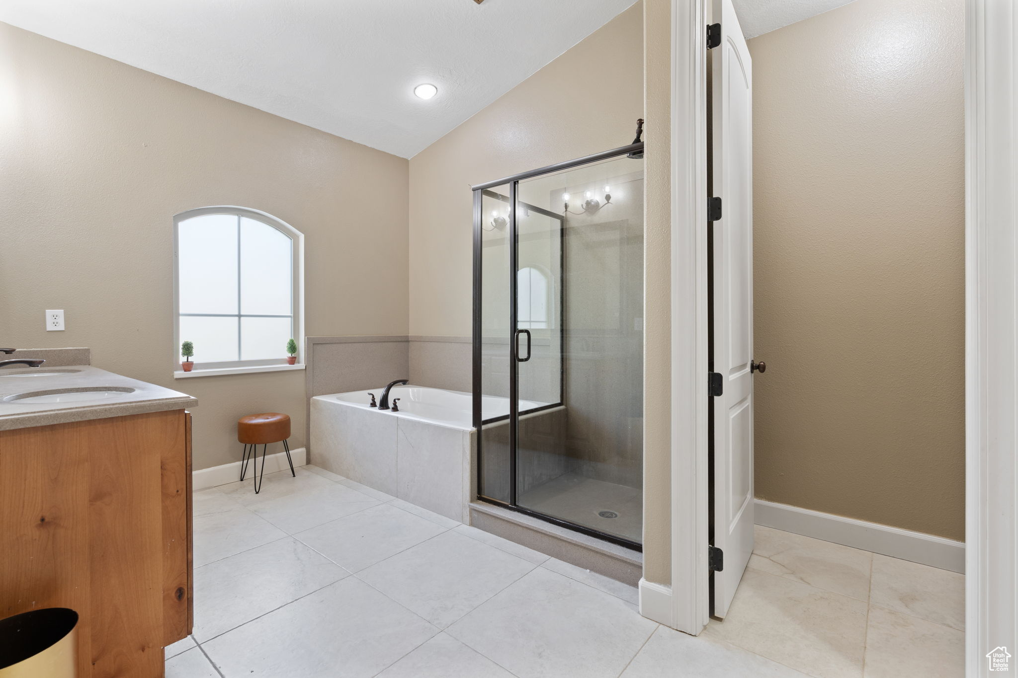 Bathroom with tile flooring, vanity, vaulted ceiling, and plus walk in shower
